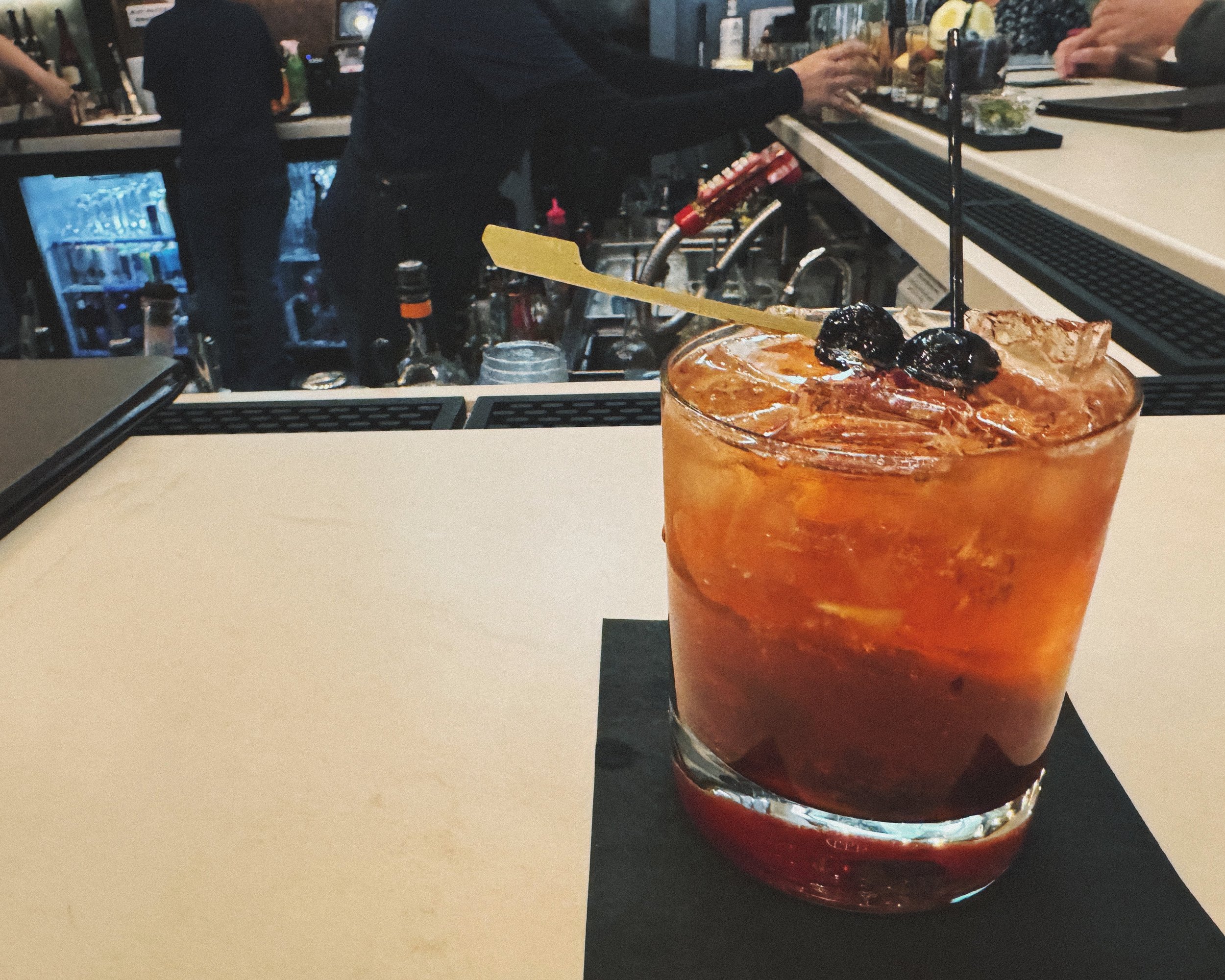 An image of a Wisconsin-style Old Fashioned cocktail served at Manny’s Parkside, featuring an orange slice, cherry, and ice in a glass tumbler.