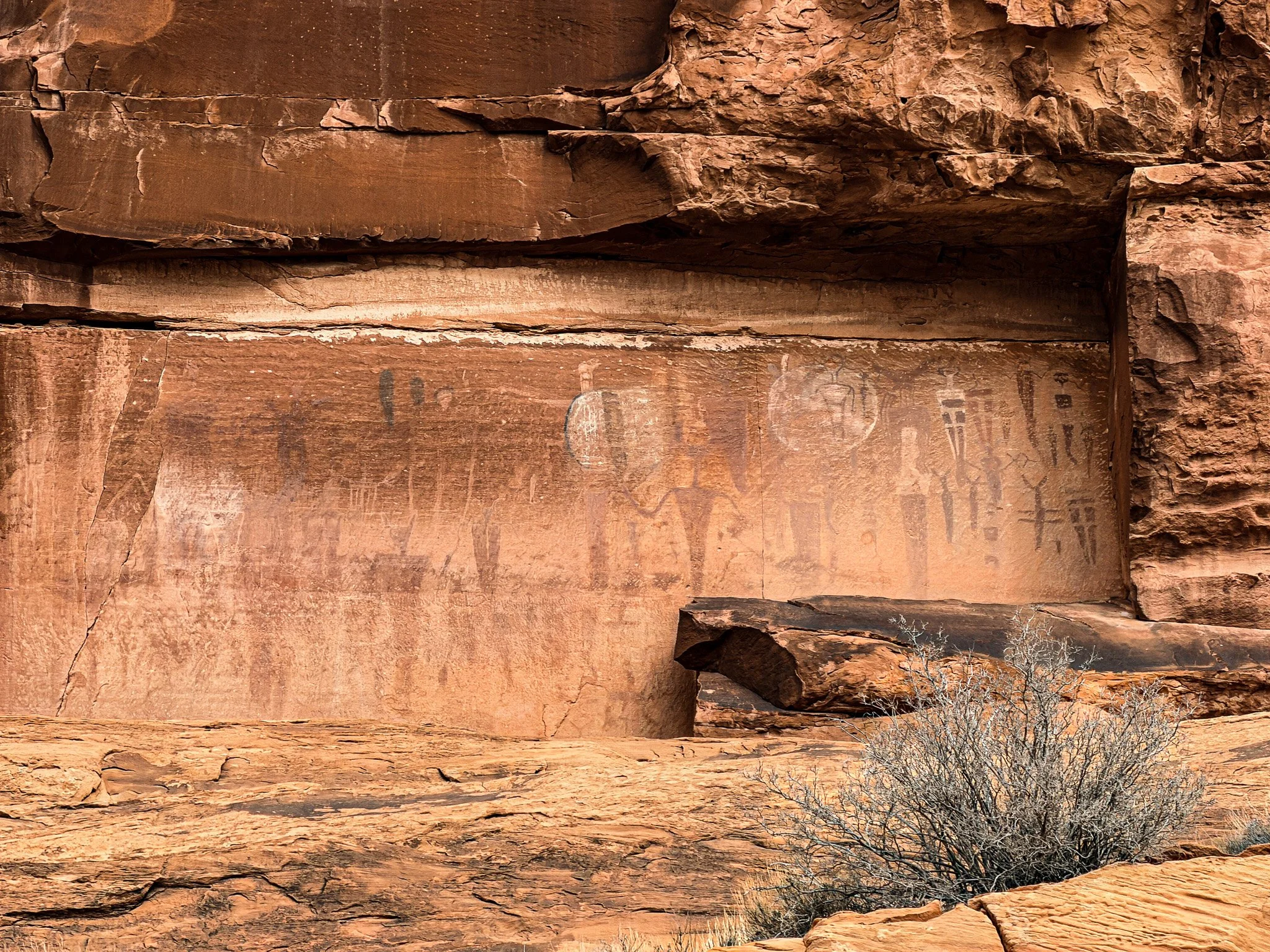 Fremont and Ute petroglyph figures on the Courthouse Wash panel near Moab, Utah, carved into a vertical sandstone cliff.