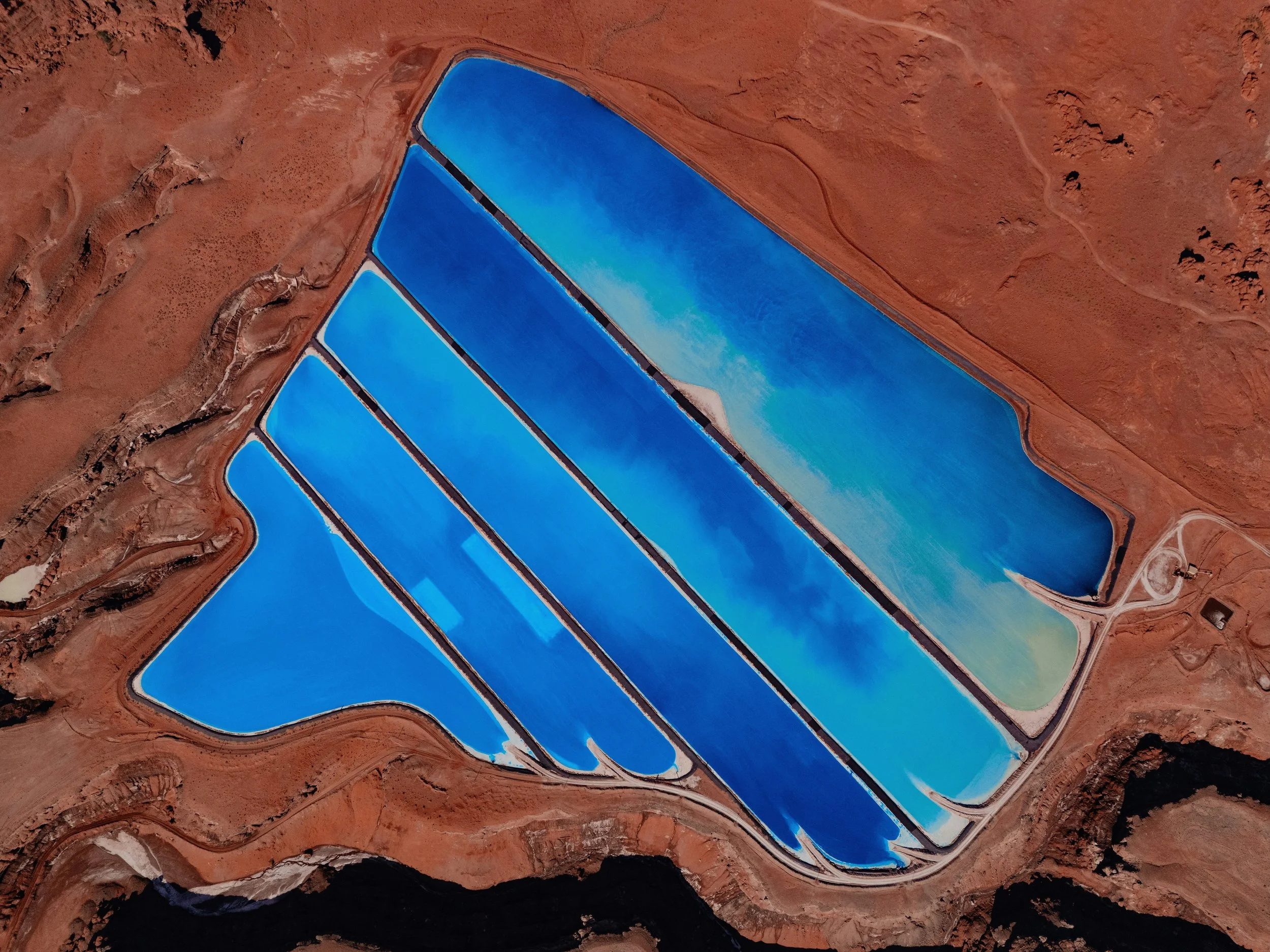 Aerial view of vivid blue potash evaporation ponds set into red desert terrain near Moab, Utah.