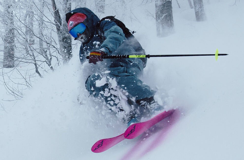 Man skiing downhill in deep powder on Corvus Freebird skis