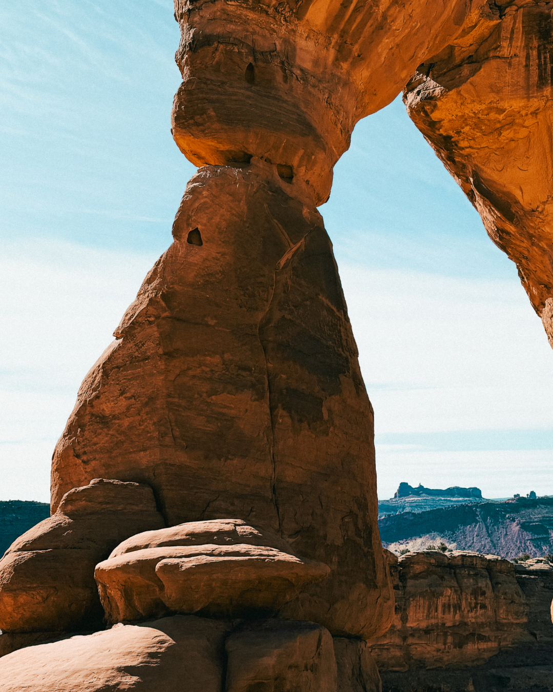 Base of Delicate Arch sandstone formation with desert canyon landscape beyond