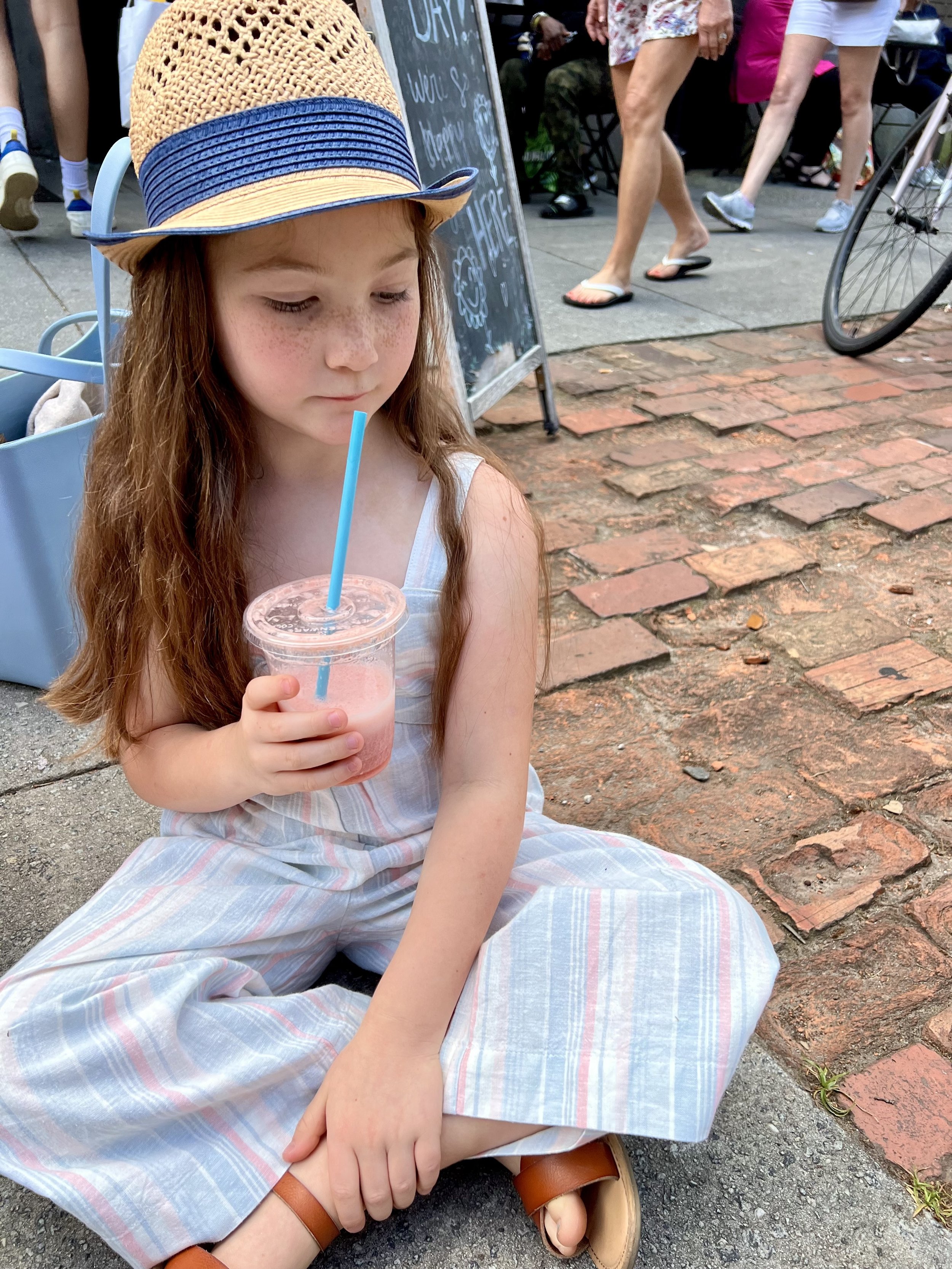 A child enjoying a fresh fruit smoothie outside Brighter Day Natural Foods Market in Savannah, Georgia, one of the city's favorite local health food stores near Forsyth Park.