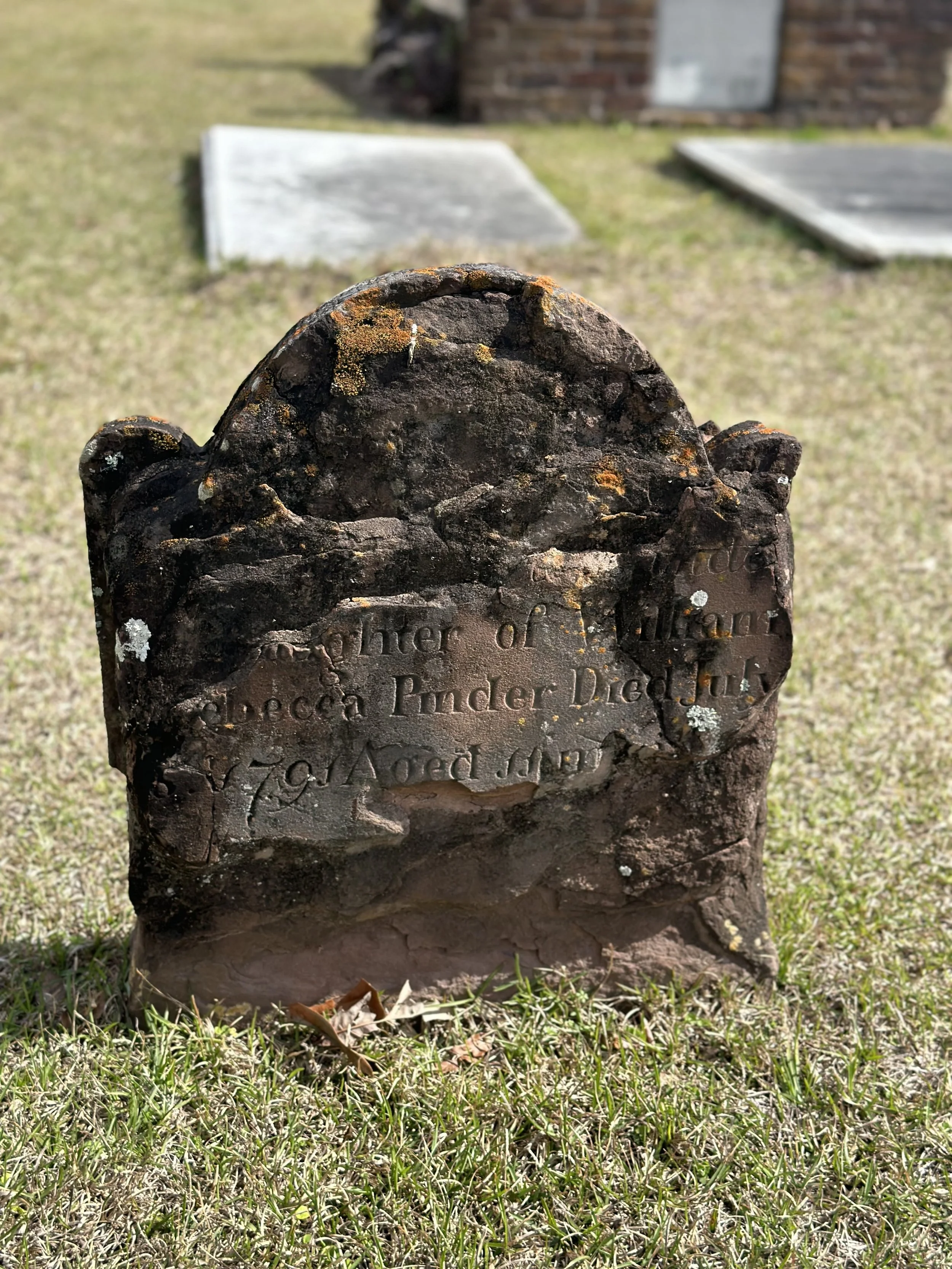Weathered historic gravestone at Bonaventure Cemetery in Savannah, Georgia, showing centuries of age and craftsmanship among the cemetery's peaceful grounds.