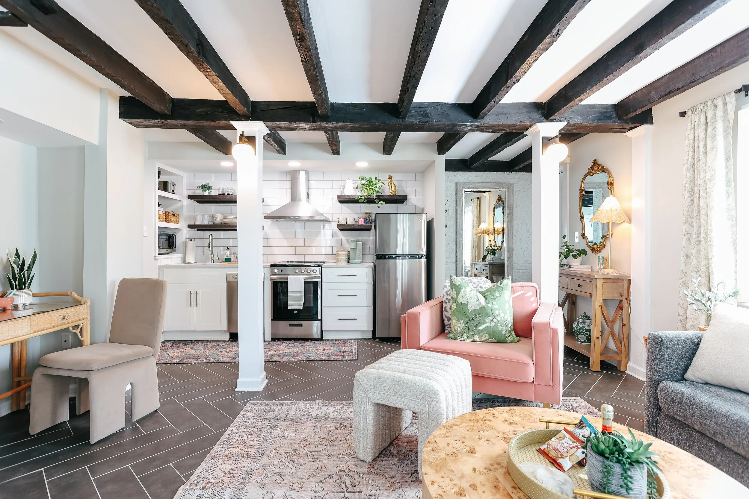 savannah luxury vacation rental on tattnall and jones street, perfect for a girls trip, savannah art, julu, herringbone floors, updated white kitchen with stainless steel appliances, pink oversized chair and stunning art decor interior design dream