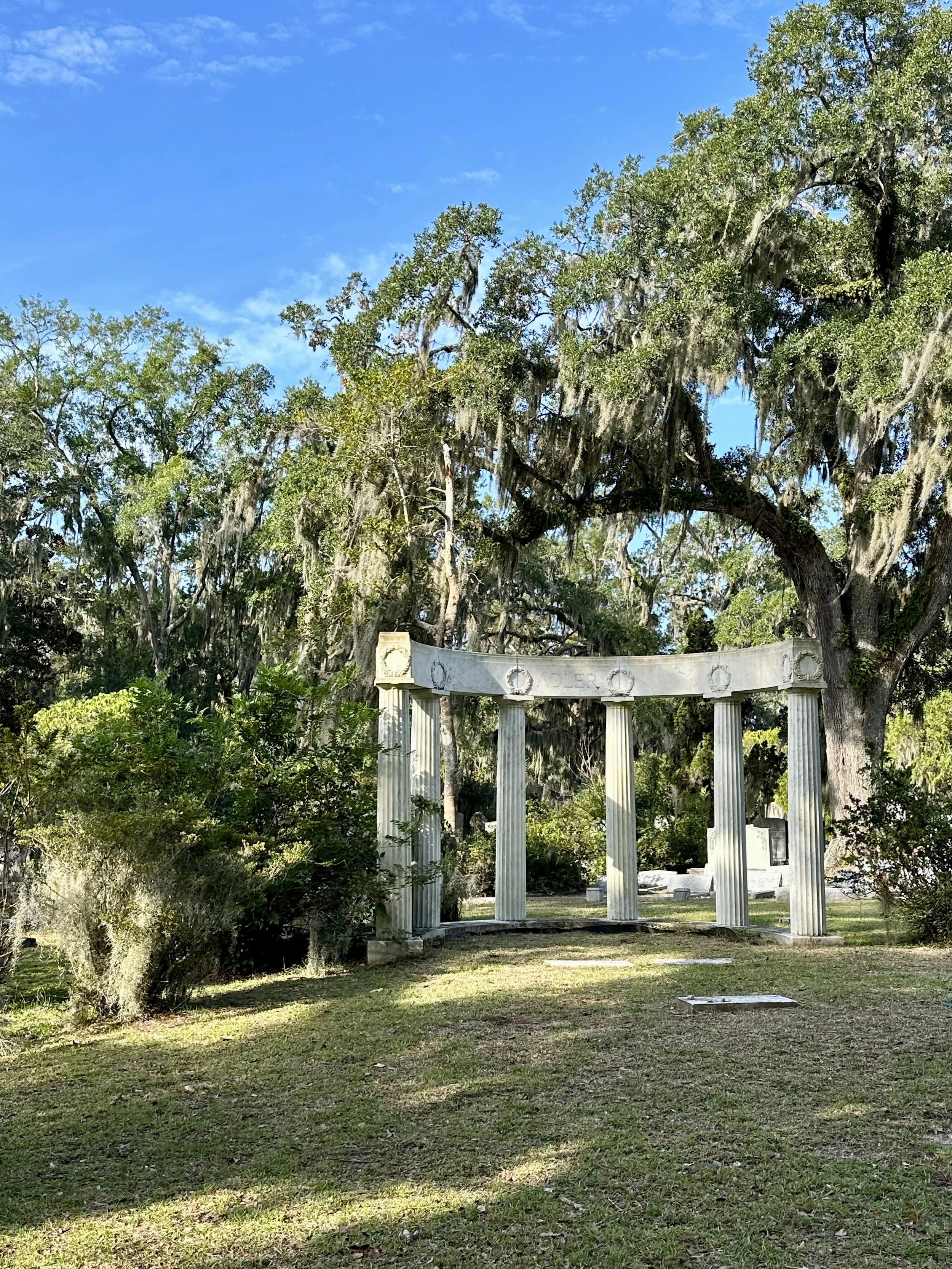 Historic Adler family memorial with classical columns surrounded by Spanish moss-covered live oak trees at Bonaventure Cemetery in Savannah, Georgia.