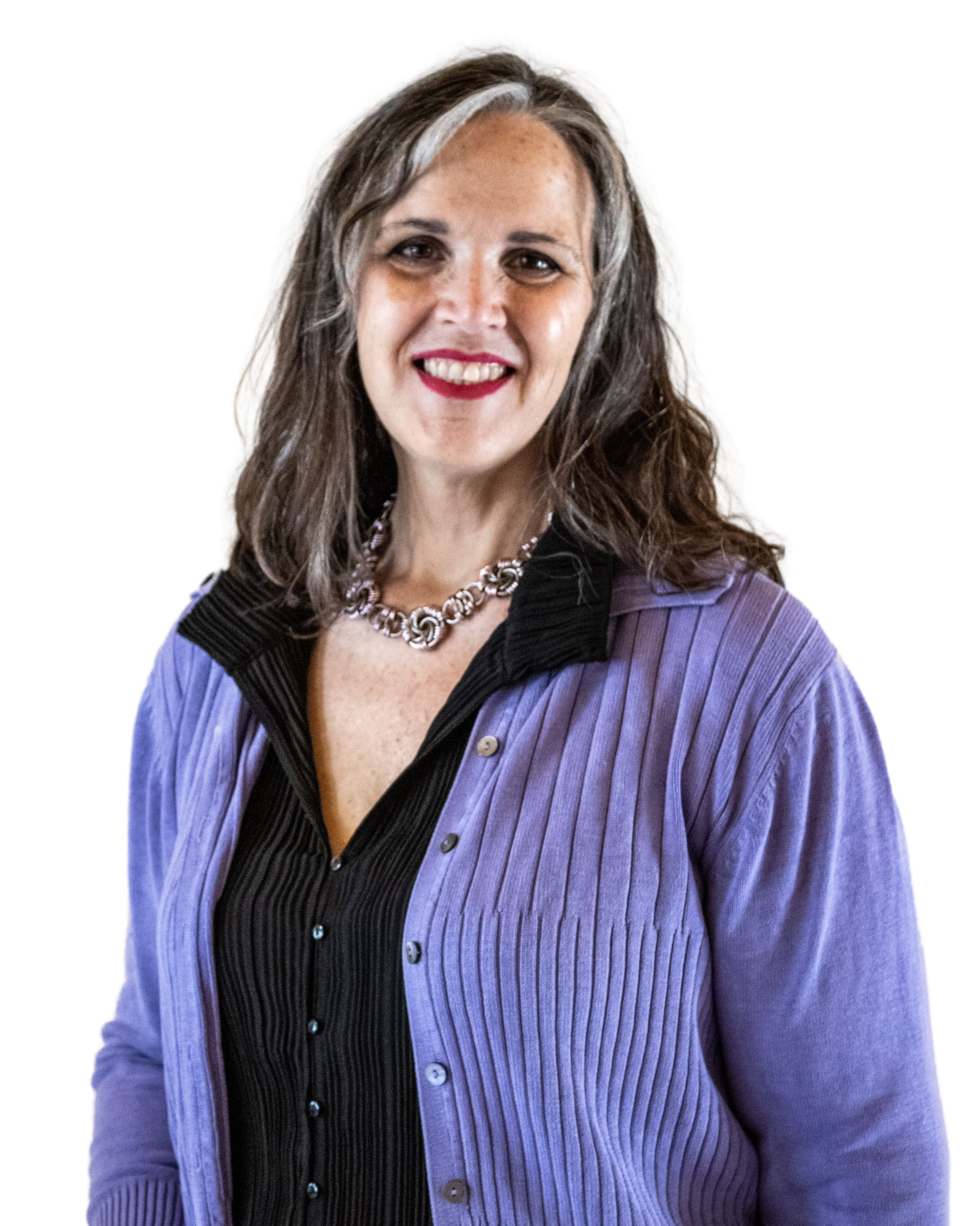 A woman with wavy, gray hair smiling, wearing a purple pinstripe blazer over a black top with a silver necklace.