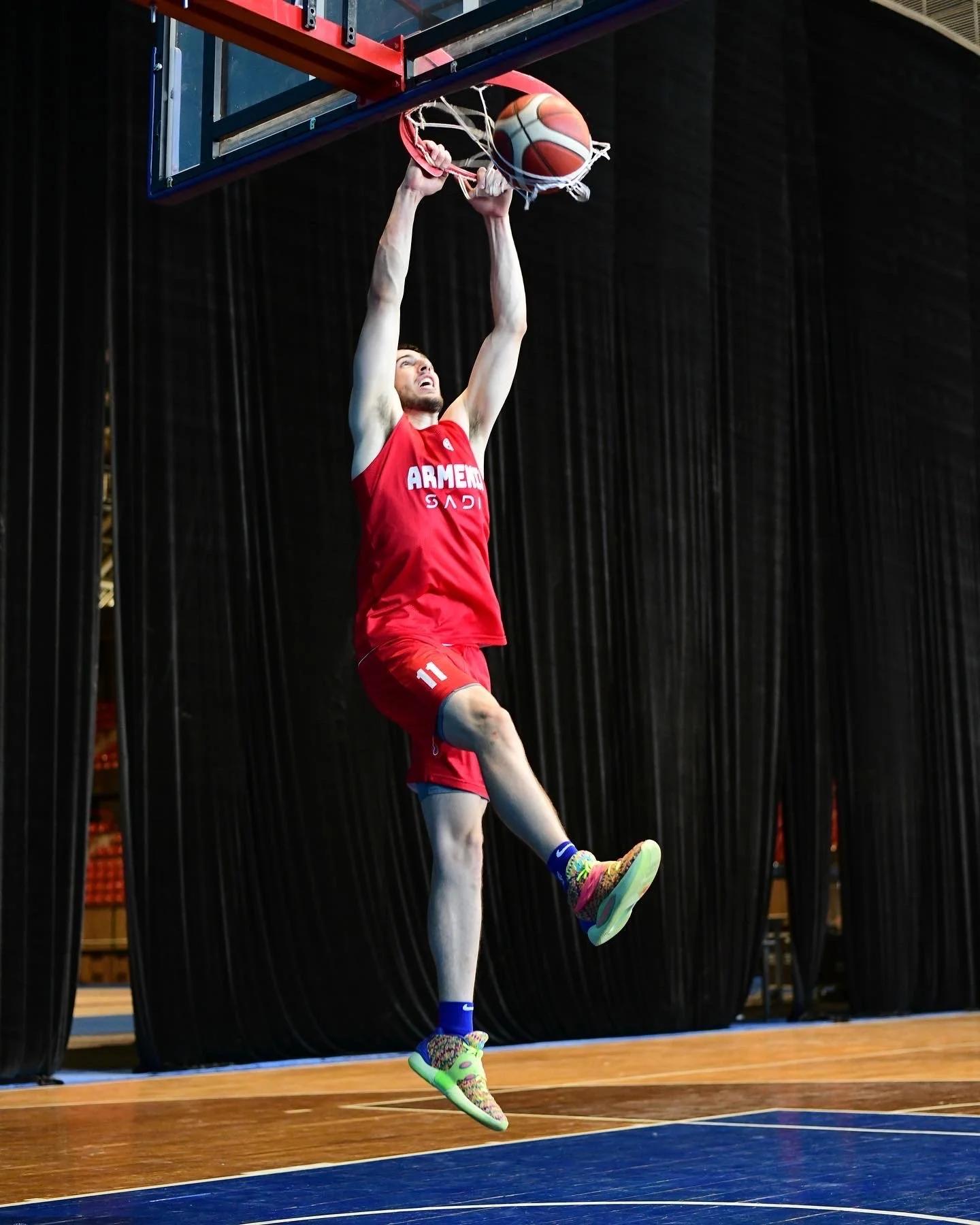 Basketball player in red uniform dunking ball during game on indoor court