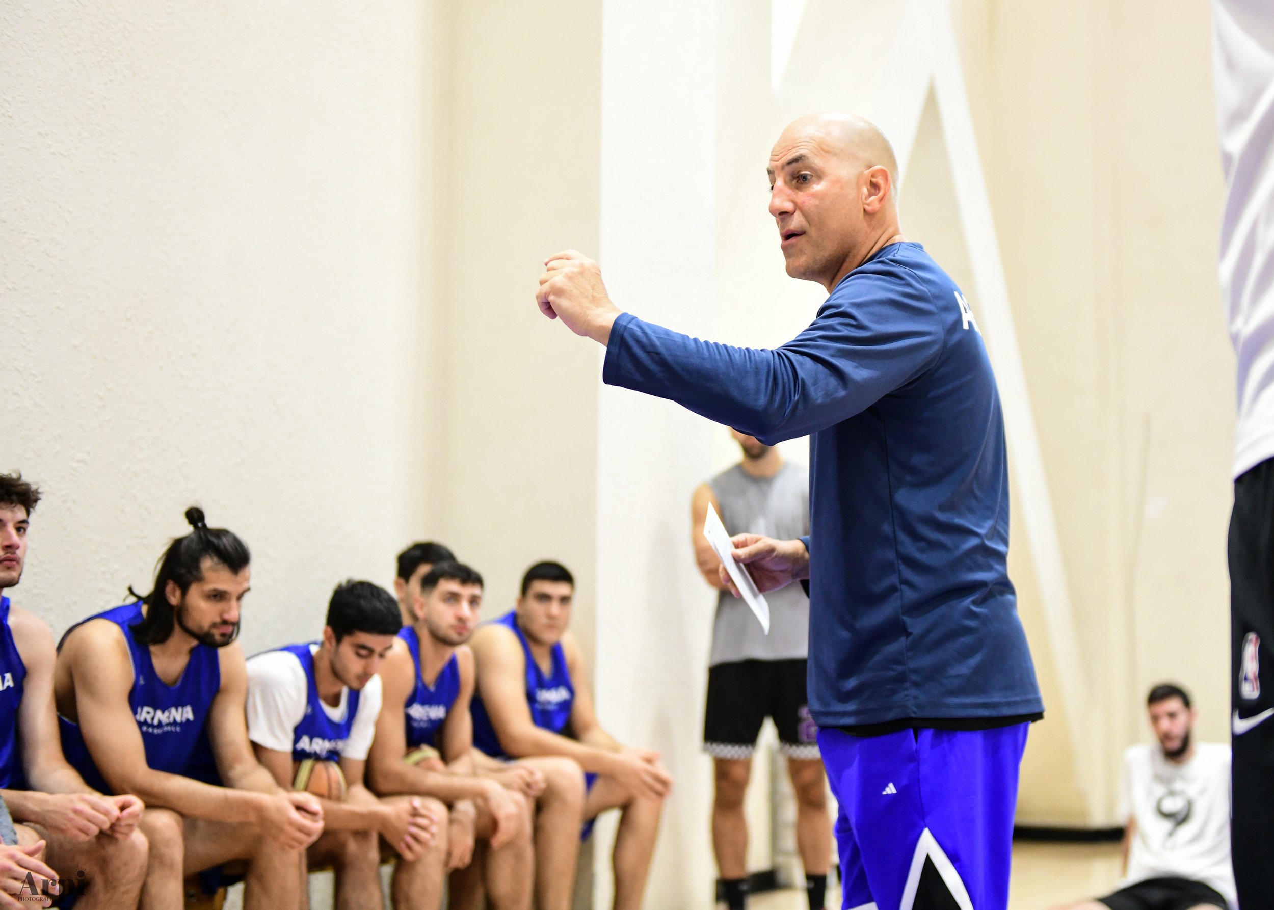 Basketball coach giving instructions to players on the bench during practice.