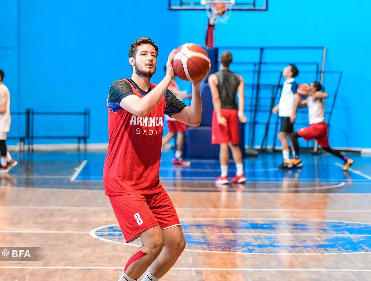 Basketball player in red jersey practicing on indoor court