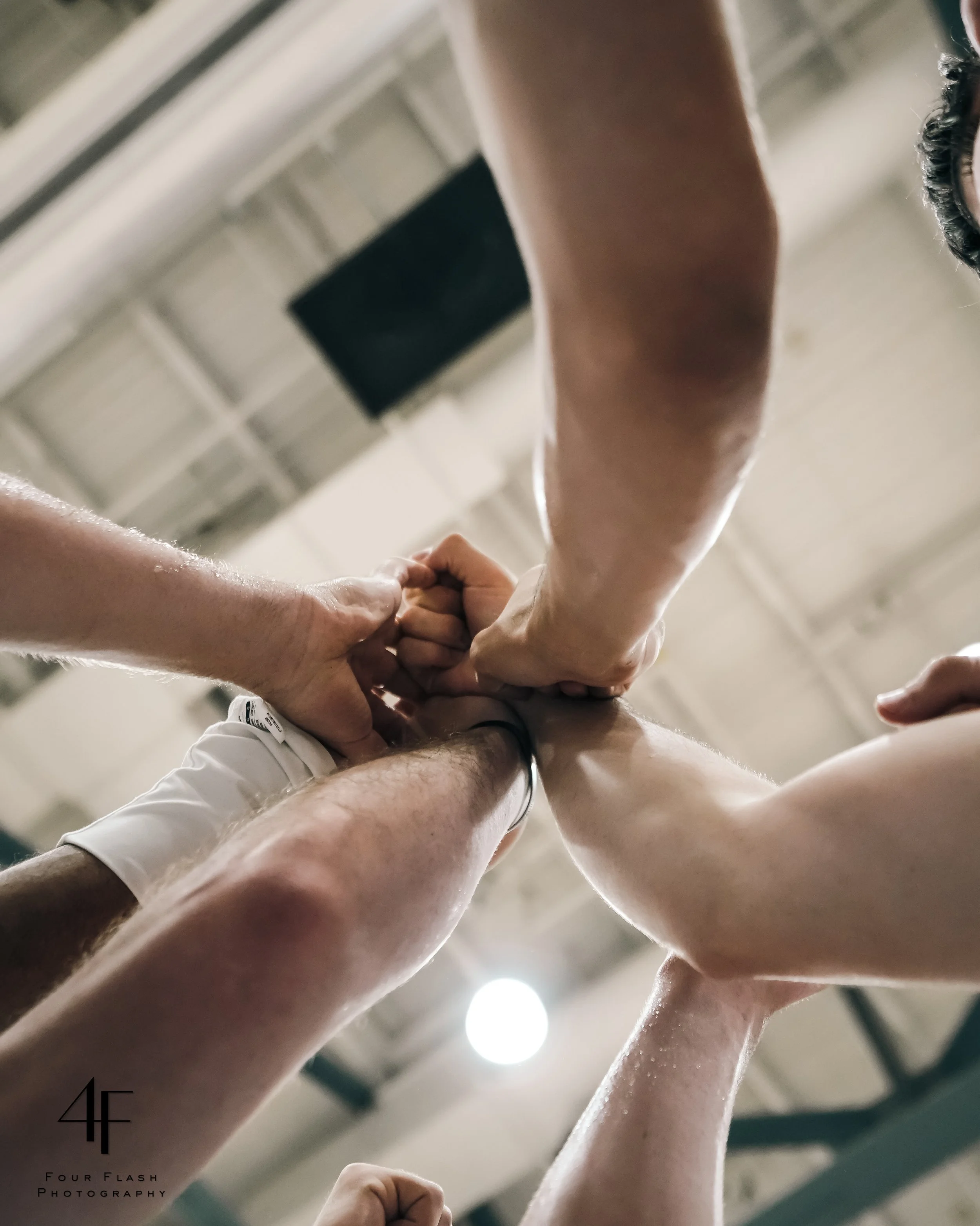 Group of people's hands joined together in a show of solidarity, viewed from below.