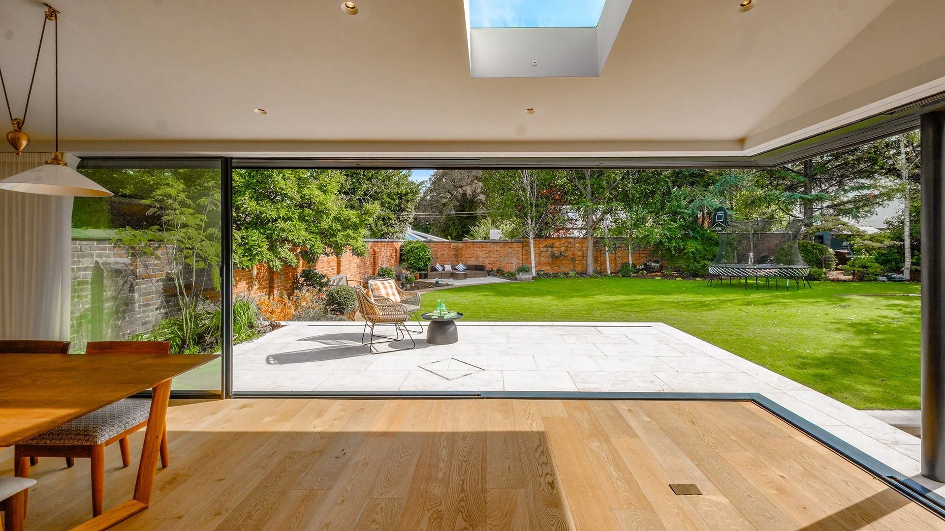 Arkipad — Contemporary home extension opening the living space onto the garden through full-width sliding glazing, creating a seamless connection between inside