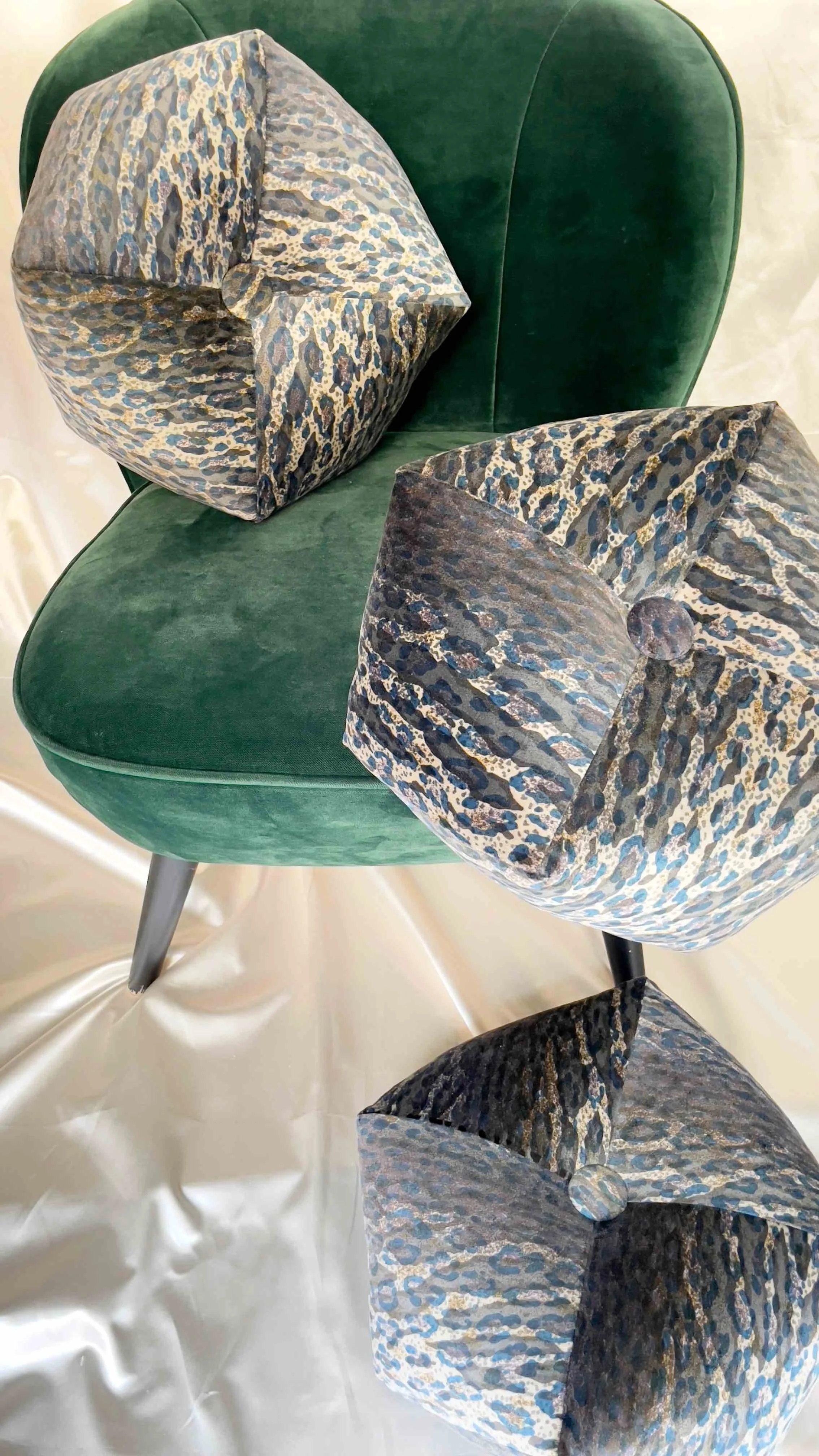 Three octagon pillows with leopard pattern on green velvet chair.
