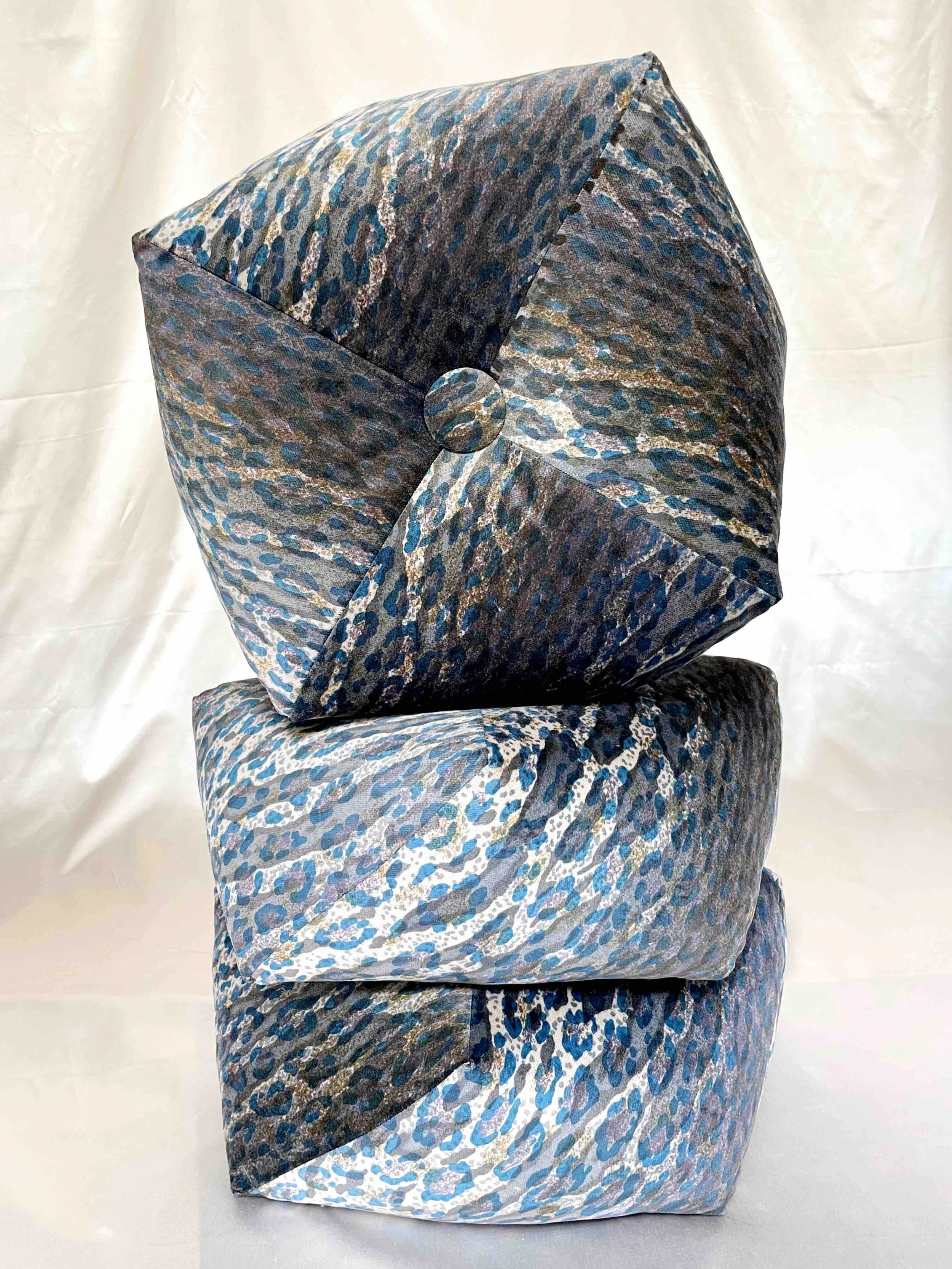Three blue and grey octagon pillows stacked on each other against a light backdrop.