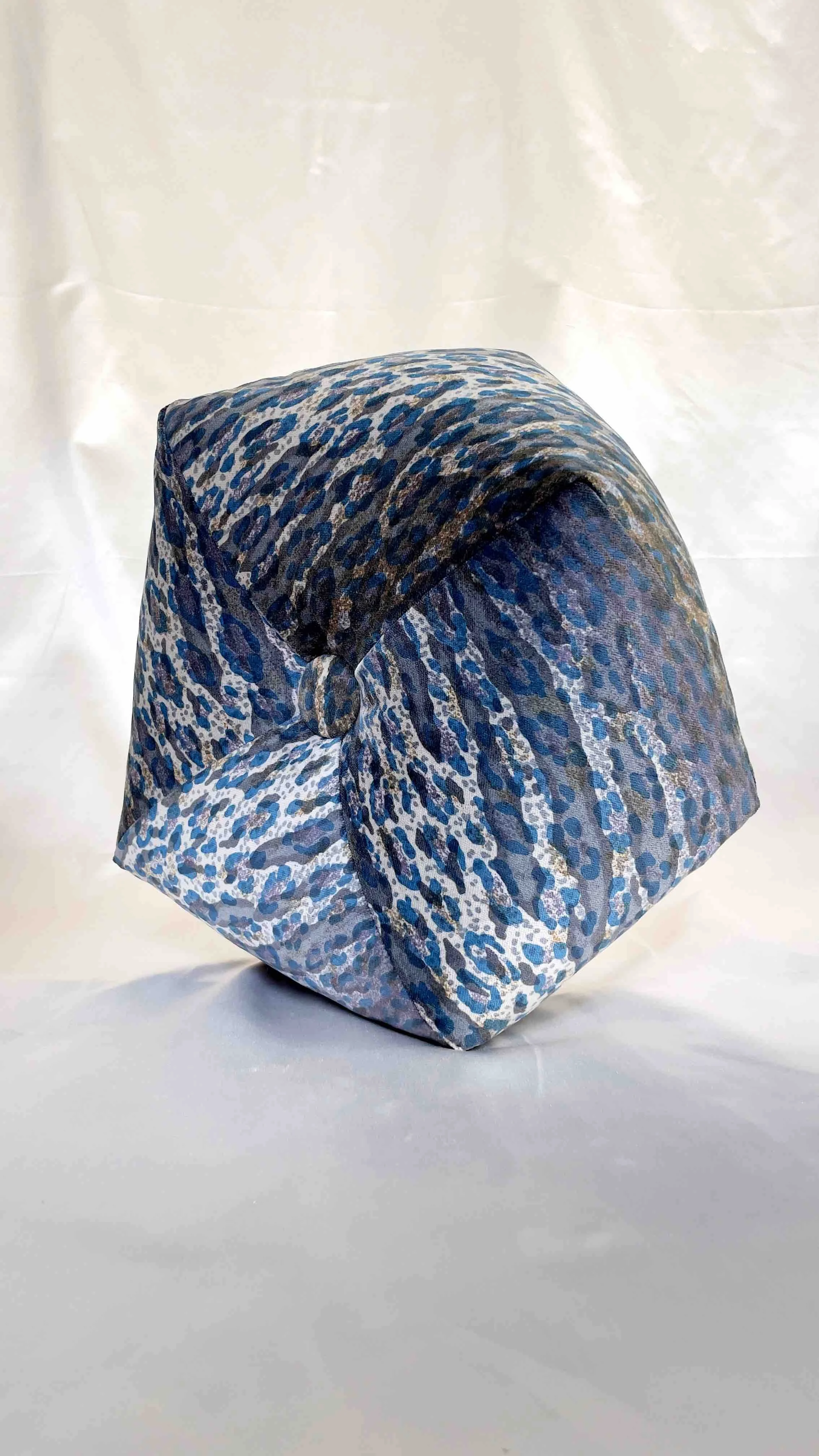 Close-up of blue and grey leopard octagon pillow on a light background.