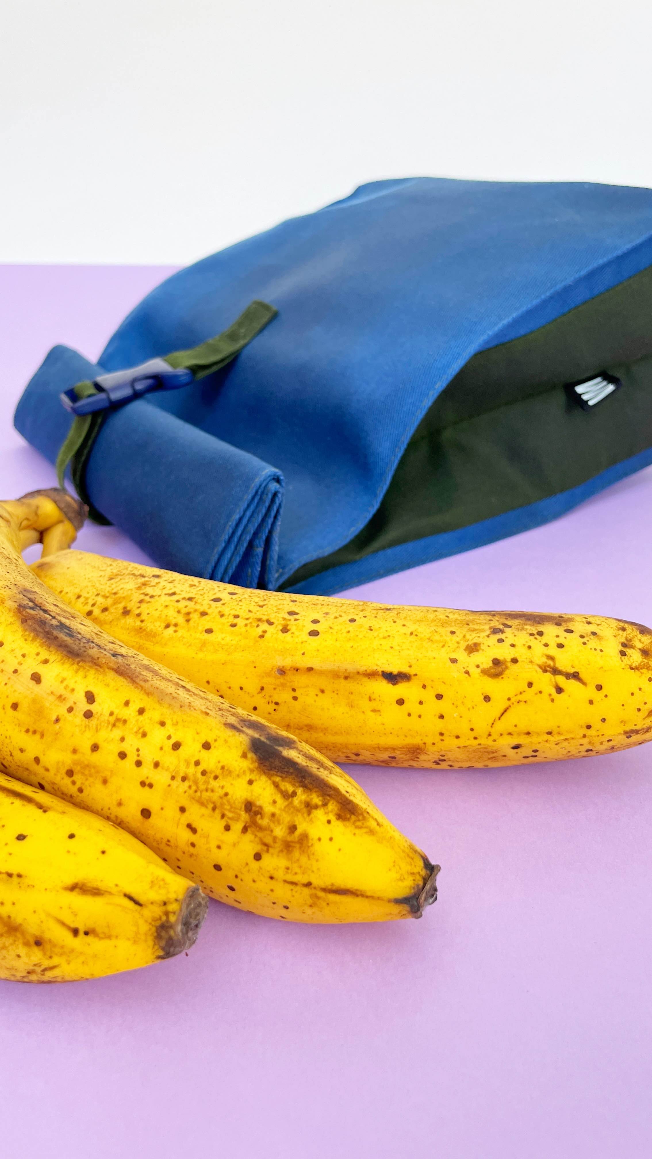 Side detail on blue beeswax bag with green details next bananas.