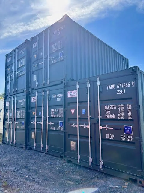 Stacked blue shipping containers outdoors under a cloudy sky.