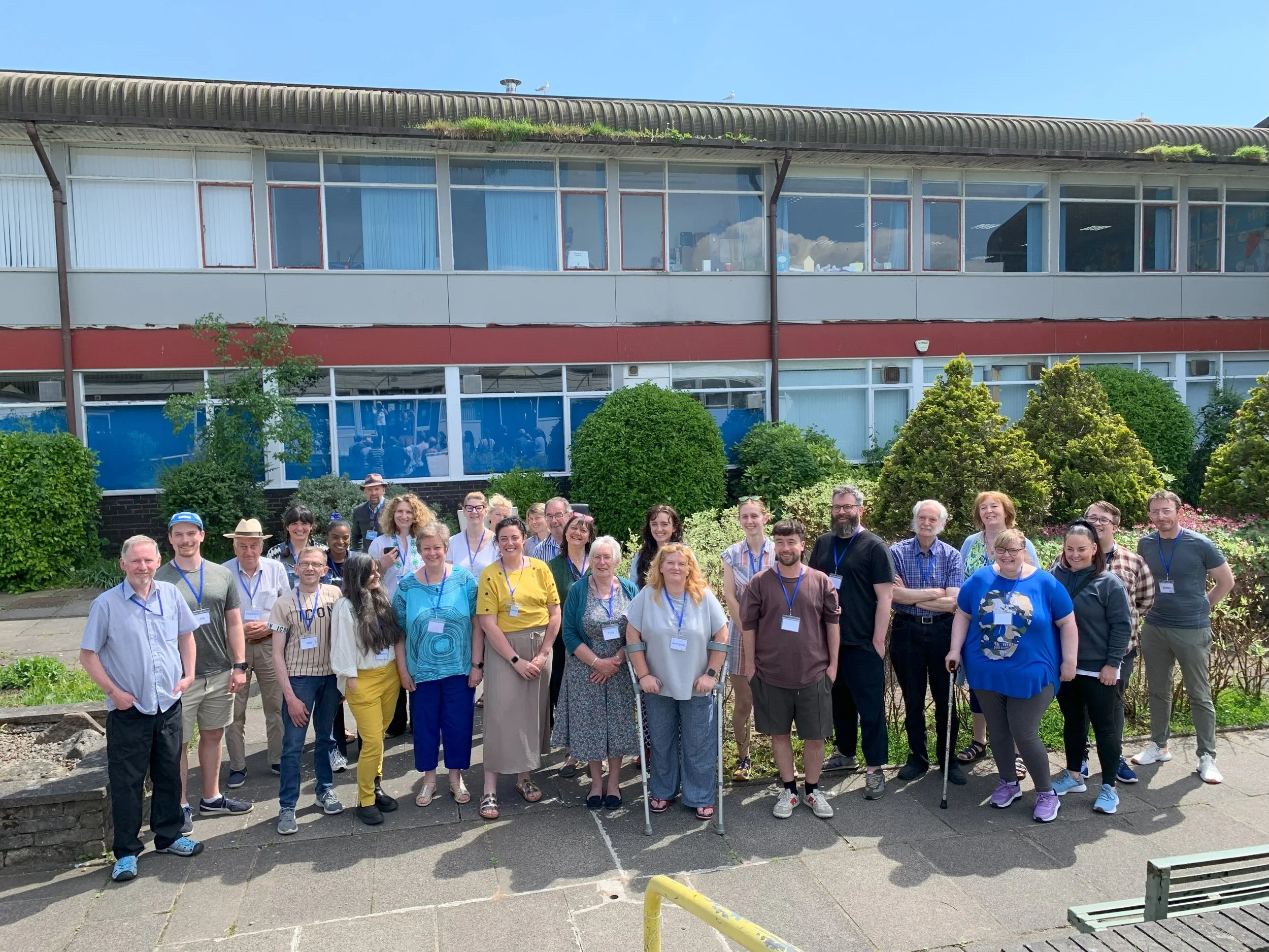 Twenty members of the jury standing together  for a photo on a sunny day