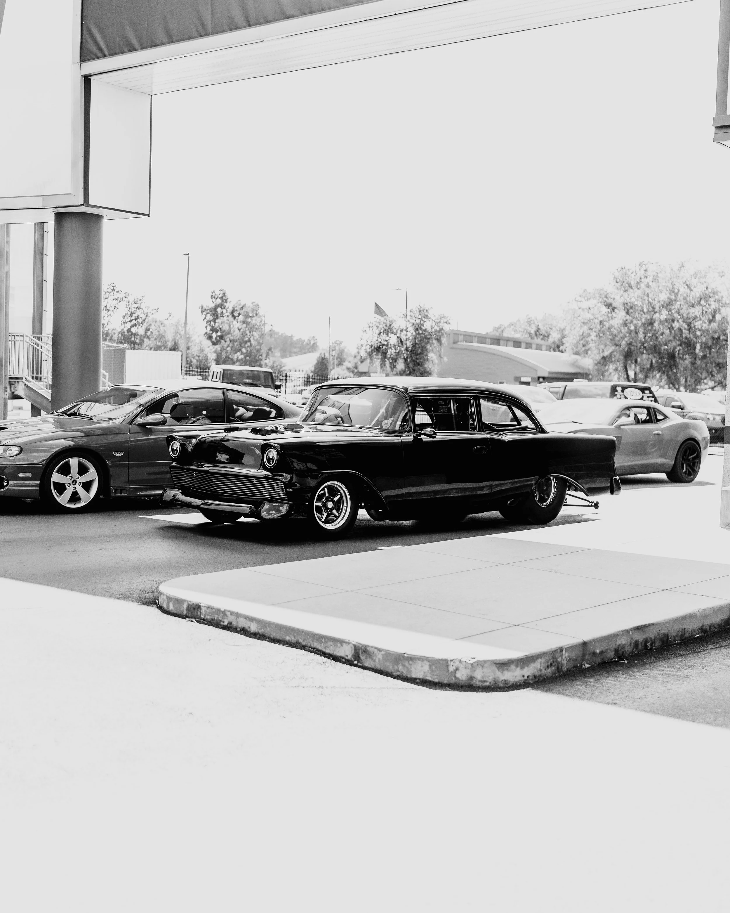 Black vintage car parked among modern cars at a parking lot.