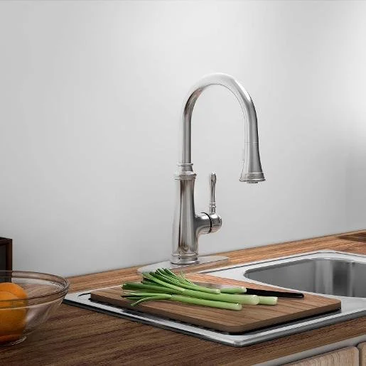 Kitchen sink with a modern silver faucet, a cutting board with chopped green onions, and a glass bowl with oranges on a wooden countertop.