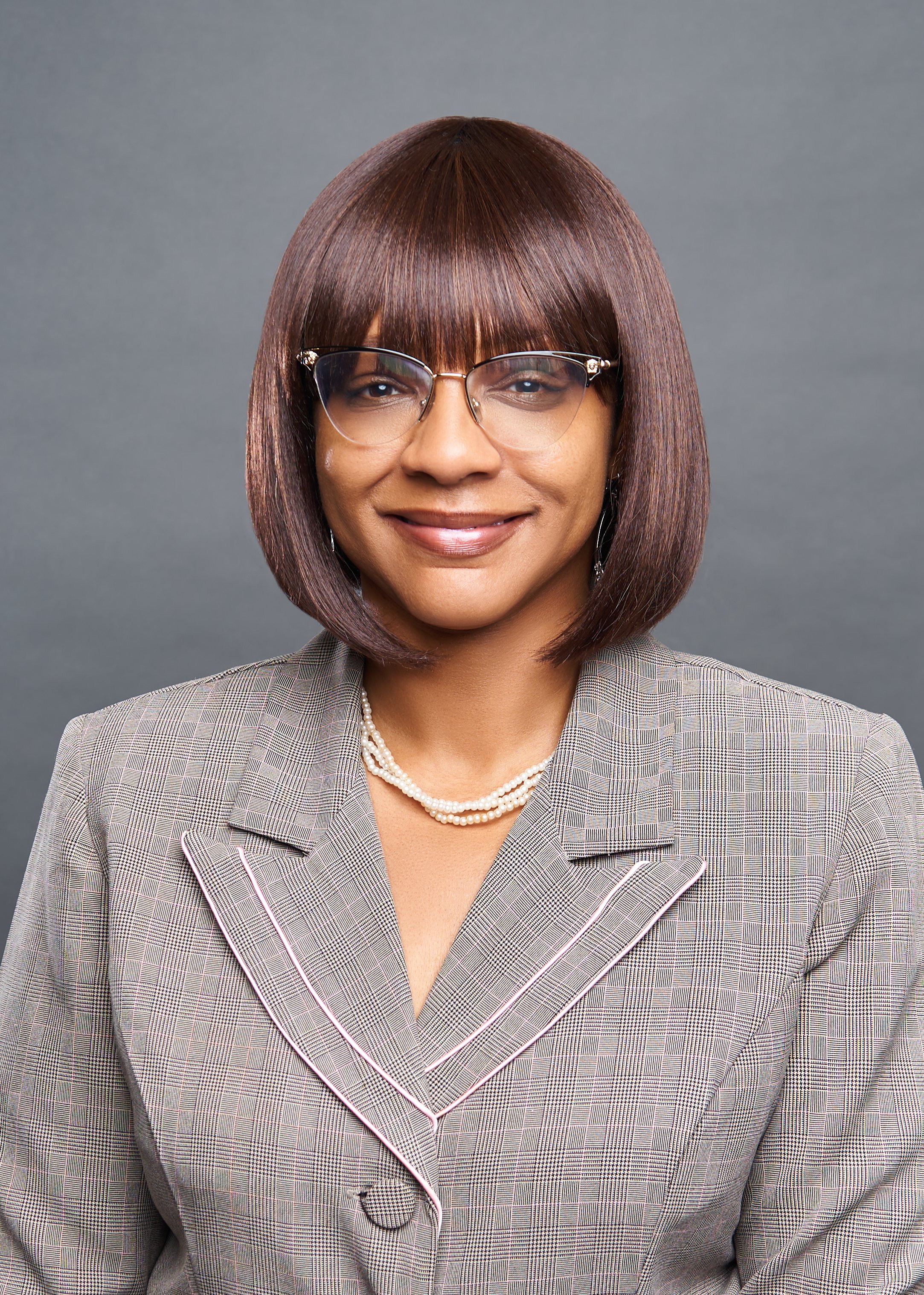 Woman wearing glasses and a suit, smiling at the camera. Hempstead Staff Headshots.