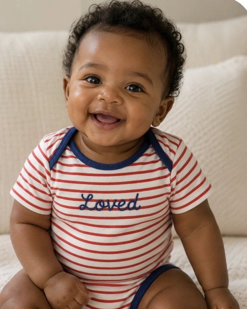 cute smiley baby wearing a hand embroidered onesie that says Loved