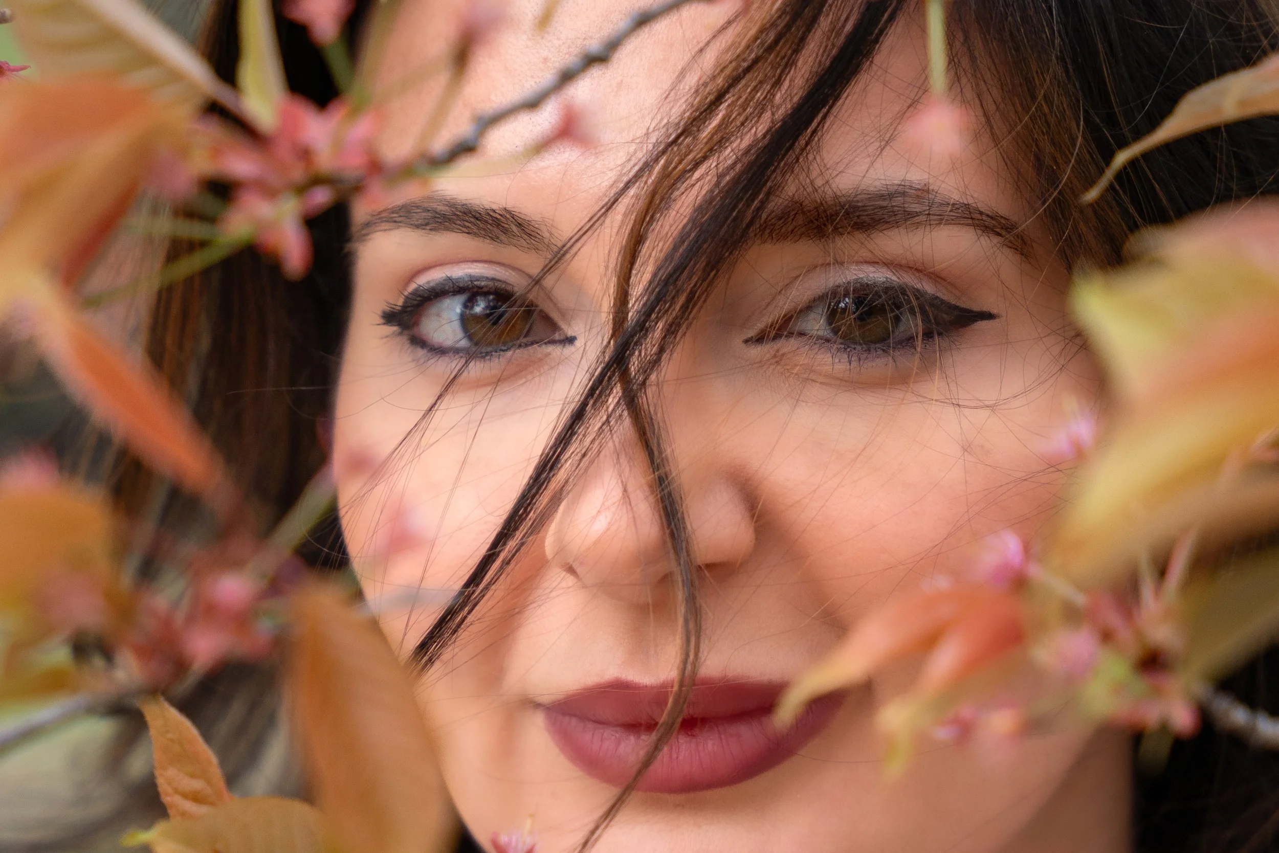 Close-up editorial portrait of Silvia framed by leaves and blossoms in Central Park NYC with soft natural light