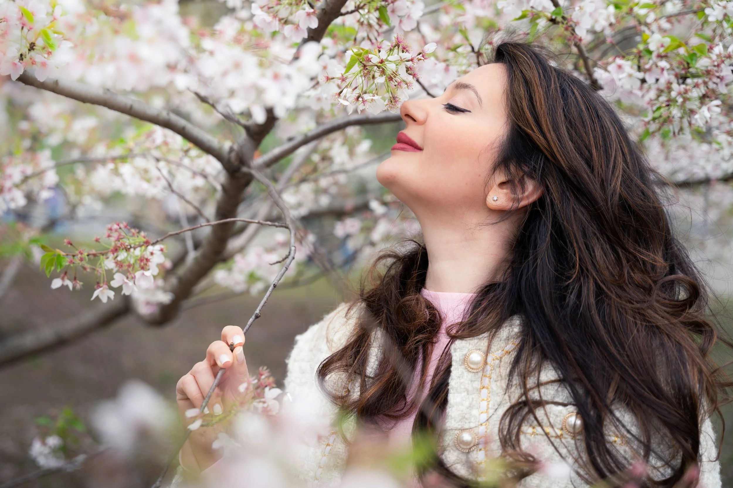 Silvia editorial portrait in Central Park under blooming cherry blossoms, profile view with soft natural light and floral surroundings