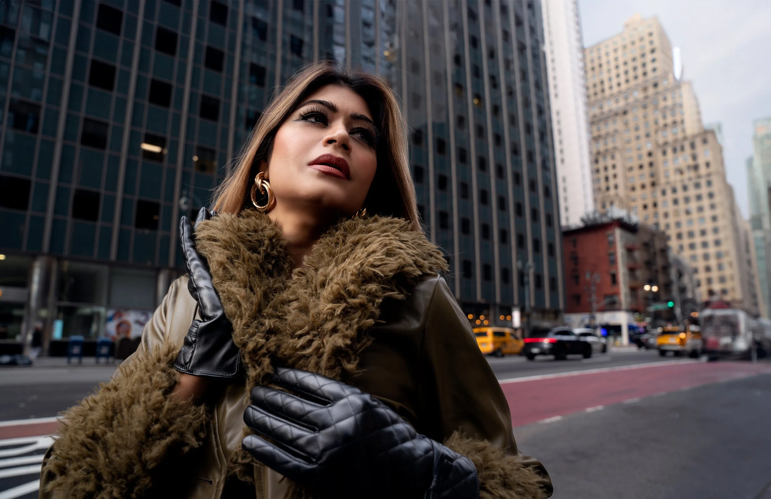 Editorial street portrait of Yesmin in a fur coat and gloves standing in a Manhattan cityscape