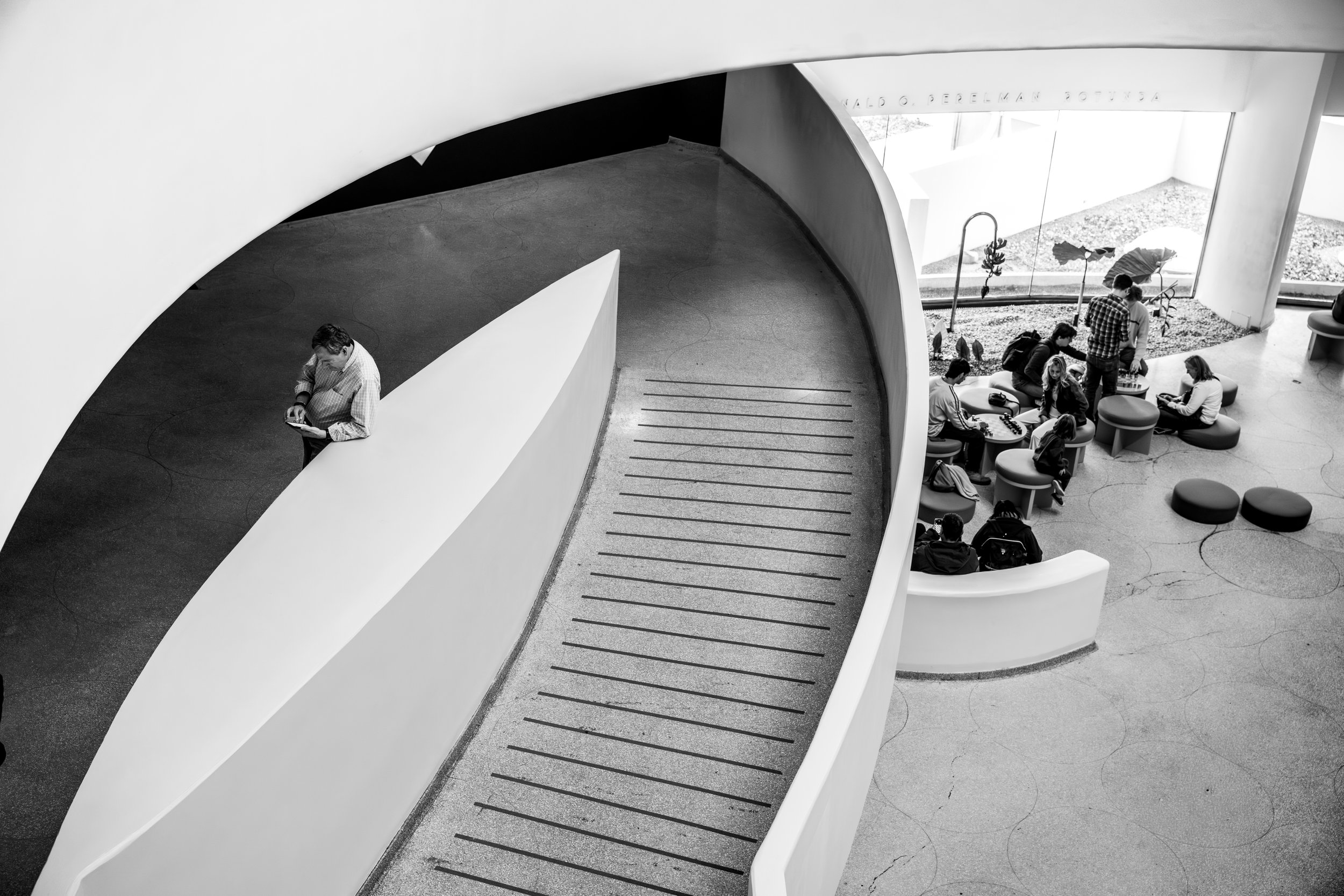 Interior ramp of the Guggenheim Museum in New York City showing organic modernist architecture with visitors interacting within the space