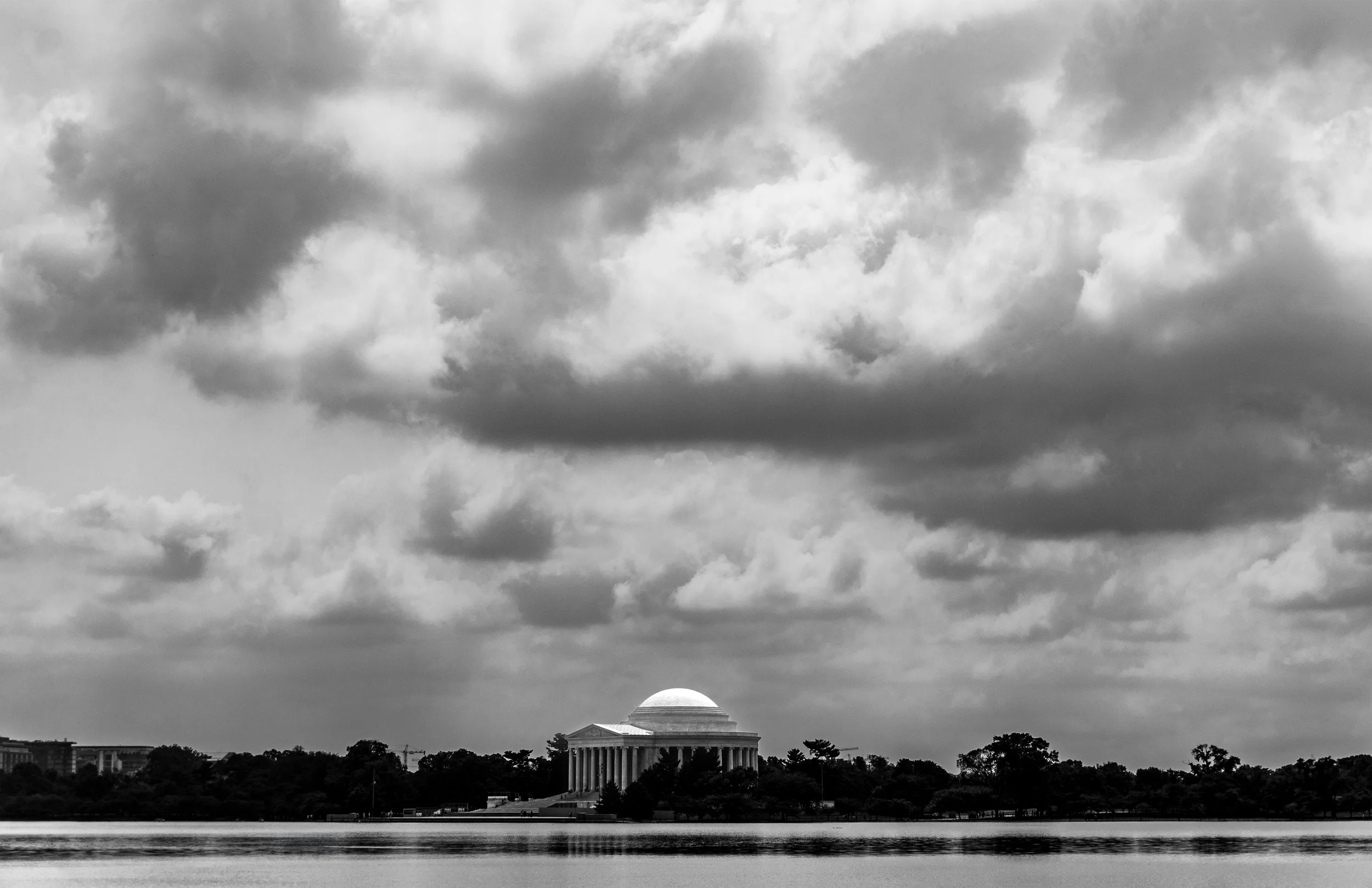 Jefferson Memorial in Washington DC featuring neoclassical architecture with domed structure and columned facade under dramatic sky