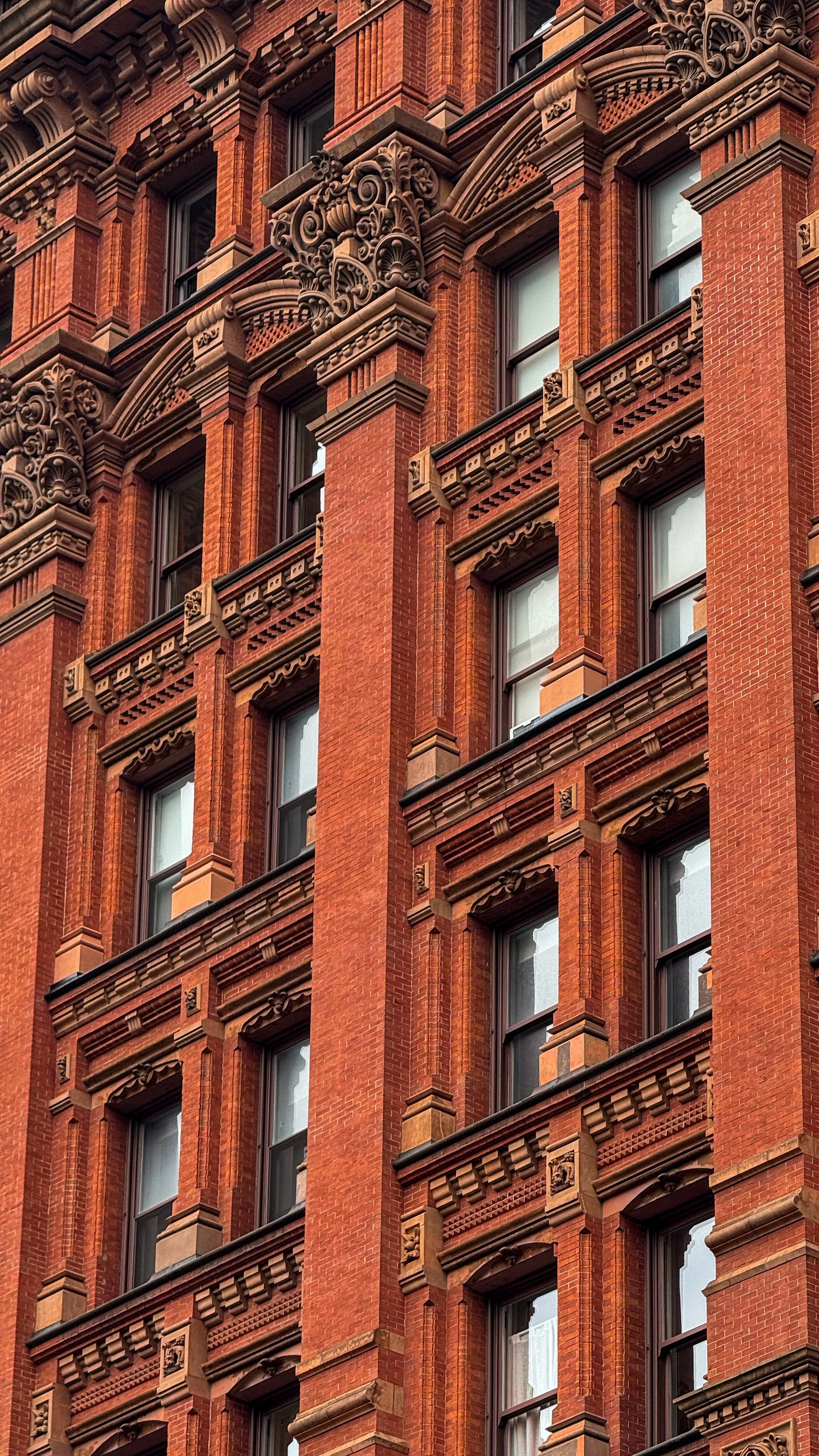Historic red brick building facade in New York City featuring Romanesque Revival architectural details and ornate stonework