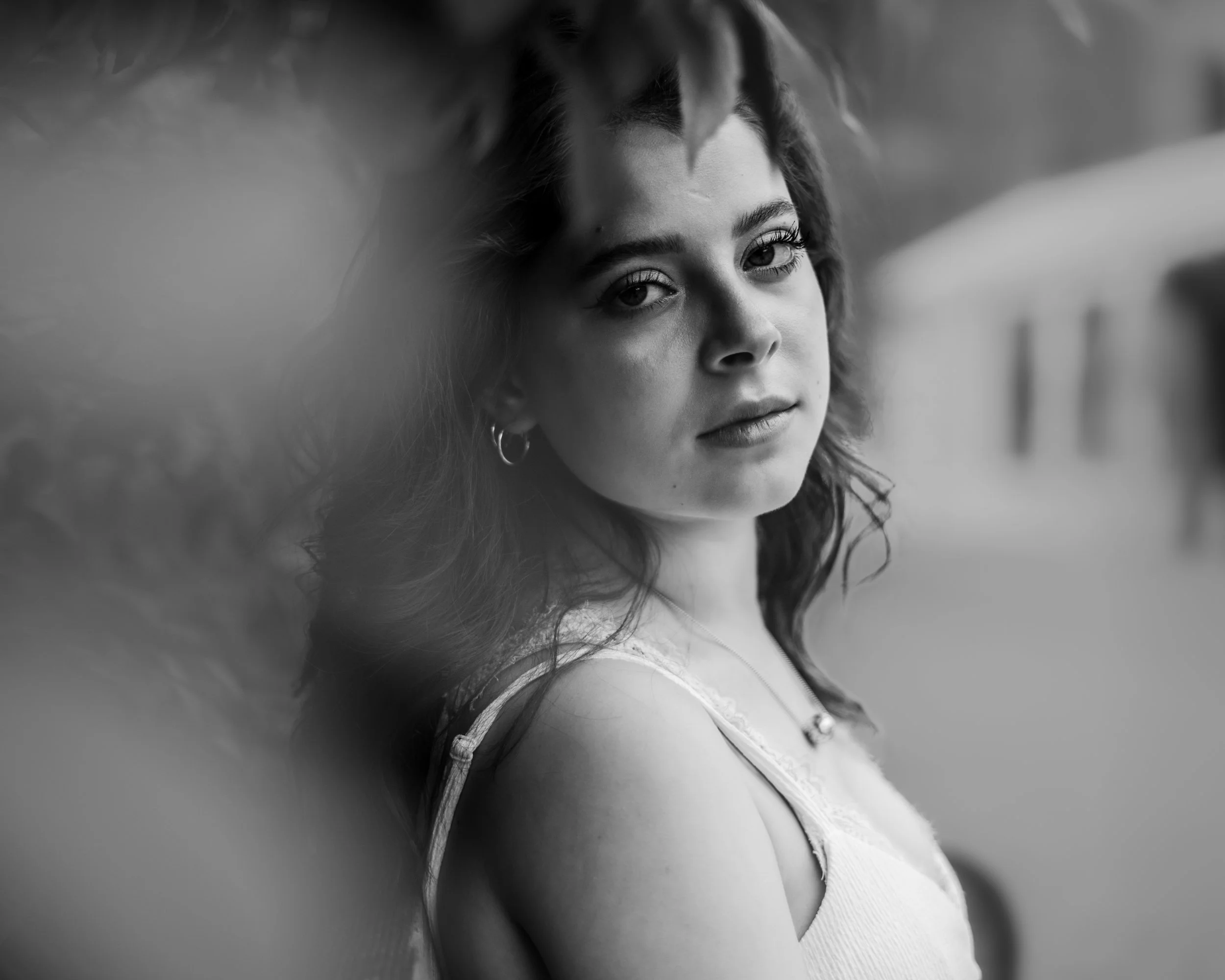 Black and white editorial portrait of Julianna with soft focus foreground and natural light