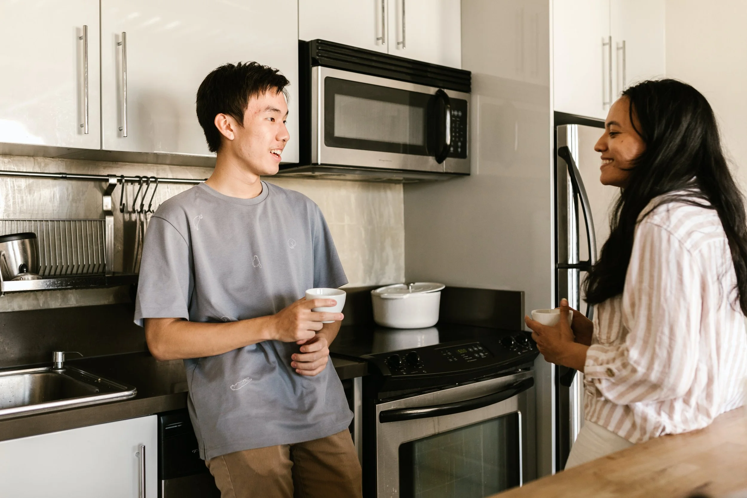 In this image we can see a couple talking in the kitchen, very happy.