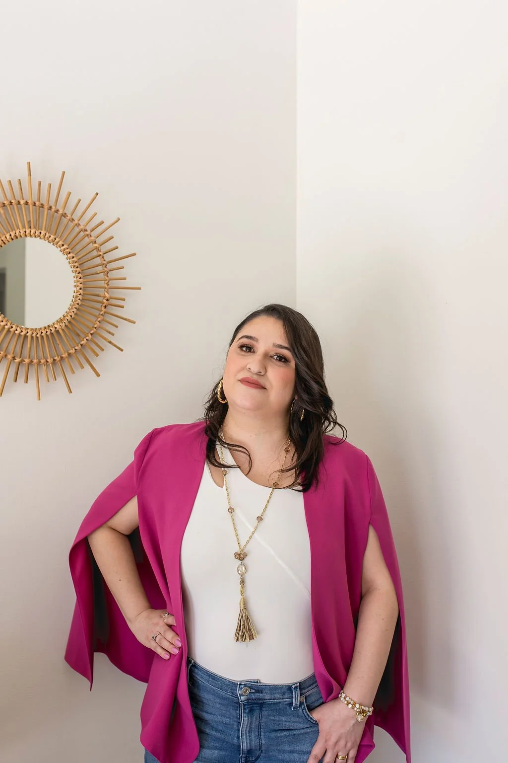 In this image we can see Mishka Kimbal LMTF, wearing her hair down, wearing a pink blazer and a white centerpiece with blue jeans