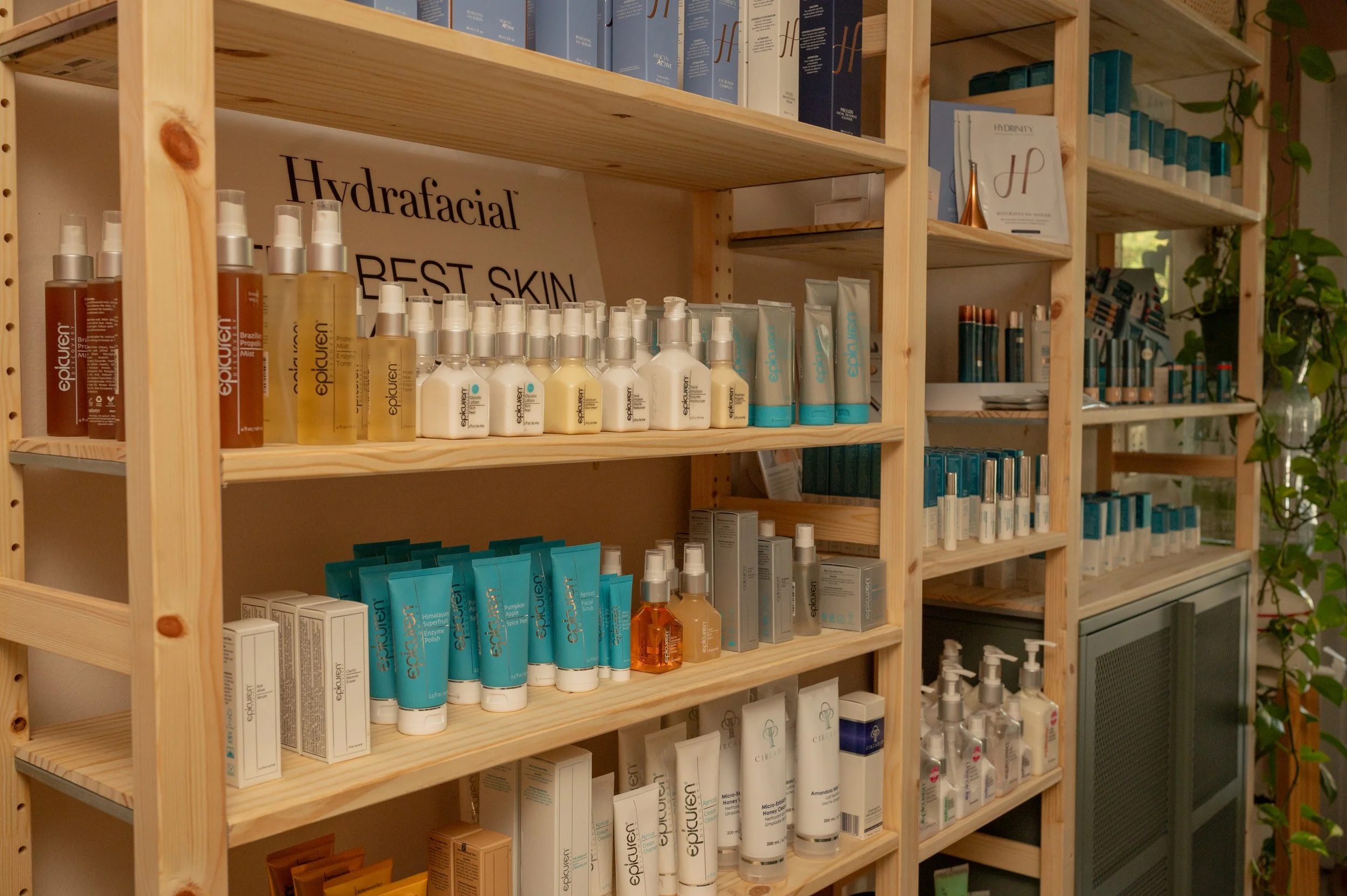 Living room with four wooden chairs, a glass coffee table, potted plants, wall art, decorative pillow and wall hanging, with an air conditioning unit.