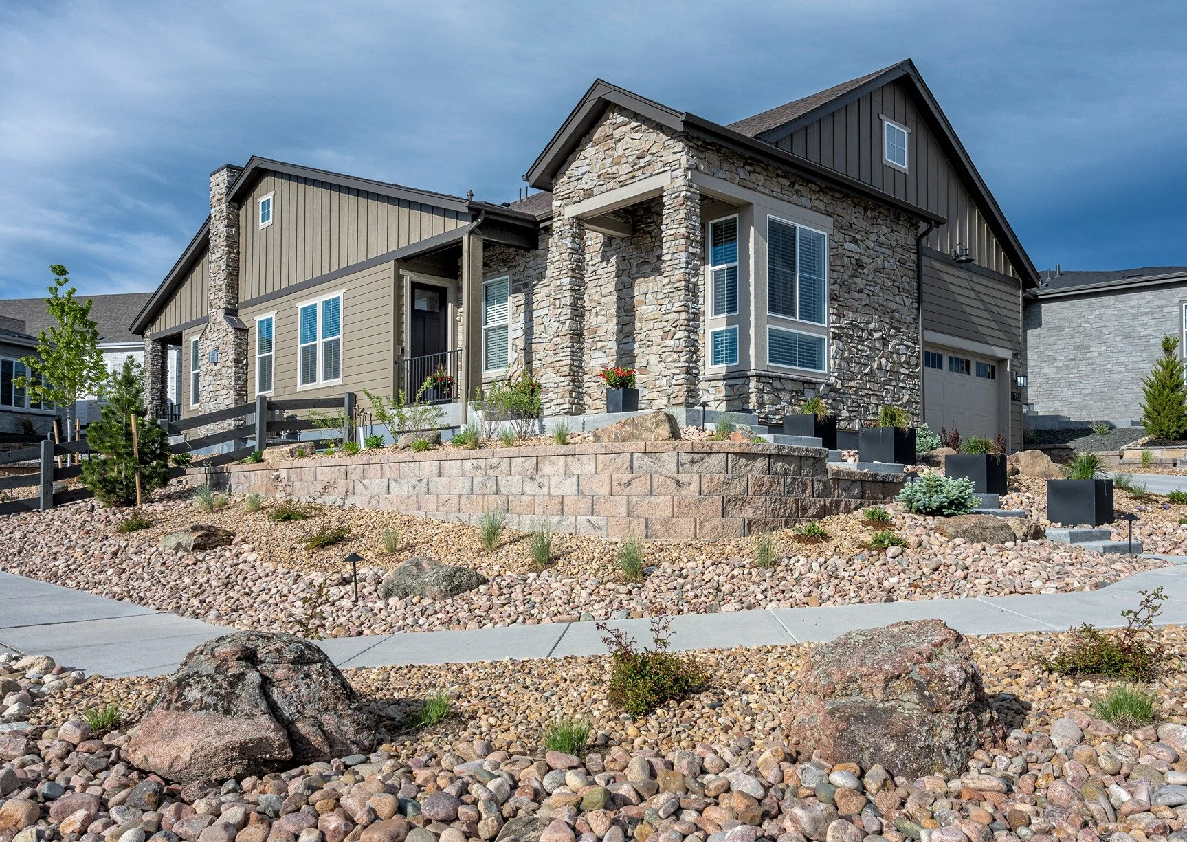 Residential xeriscape design in Highlands Ranch with decorative rock landscaping, retaining wall, and drought-tolerant plants.