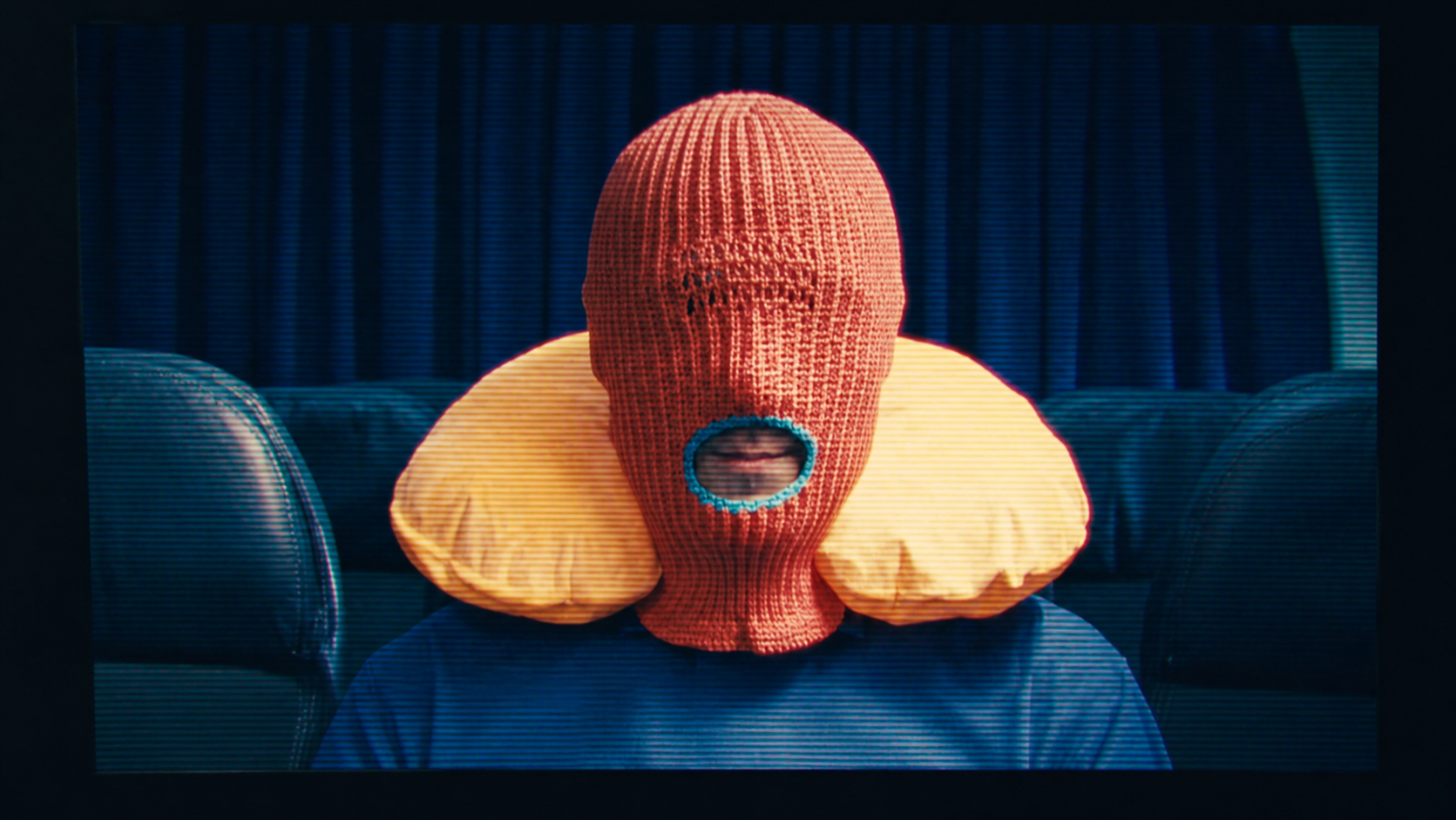 Brother Mouth wearing an orange Mouth-Clava and yellow neck pillow.