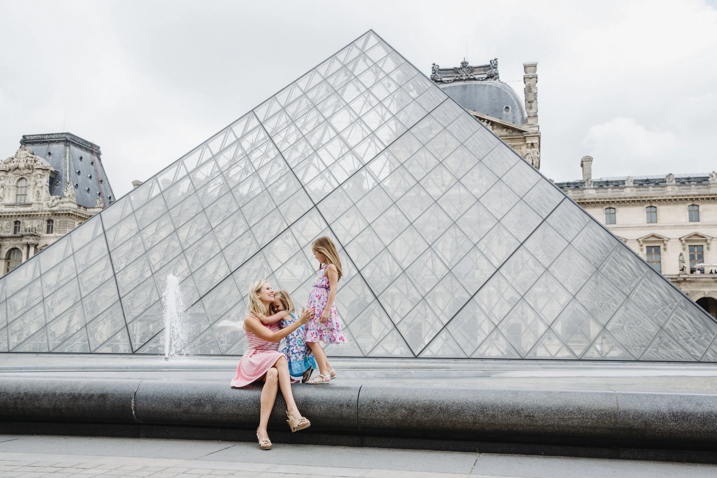 Mother and two daughters beside the Louvre Pyramid and fountain in Paris, France
