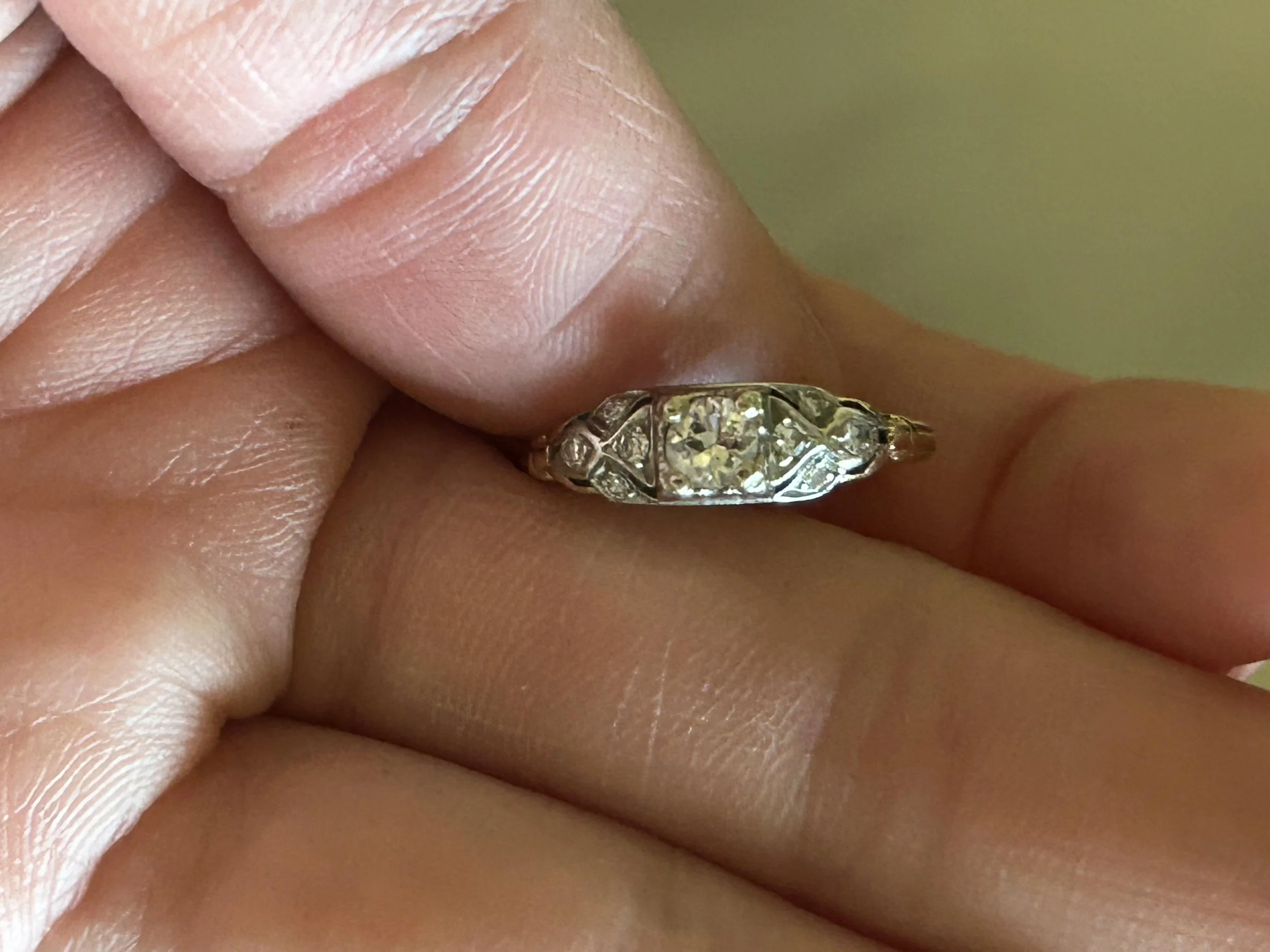 Close-up of a vintage diamond heirloom ring held in hand, showing an antique-inspired setting and the details considered during a Gerard Rene jewelry redesign consultation.