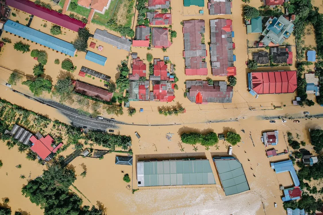 Aerial image of a flooded town, with rooftops visible above brown floodwaters