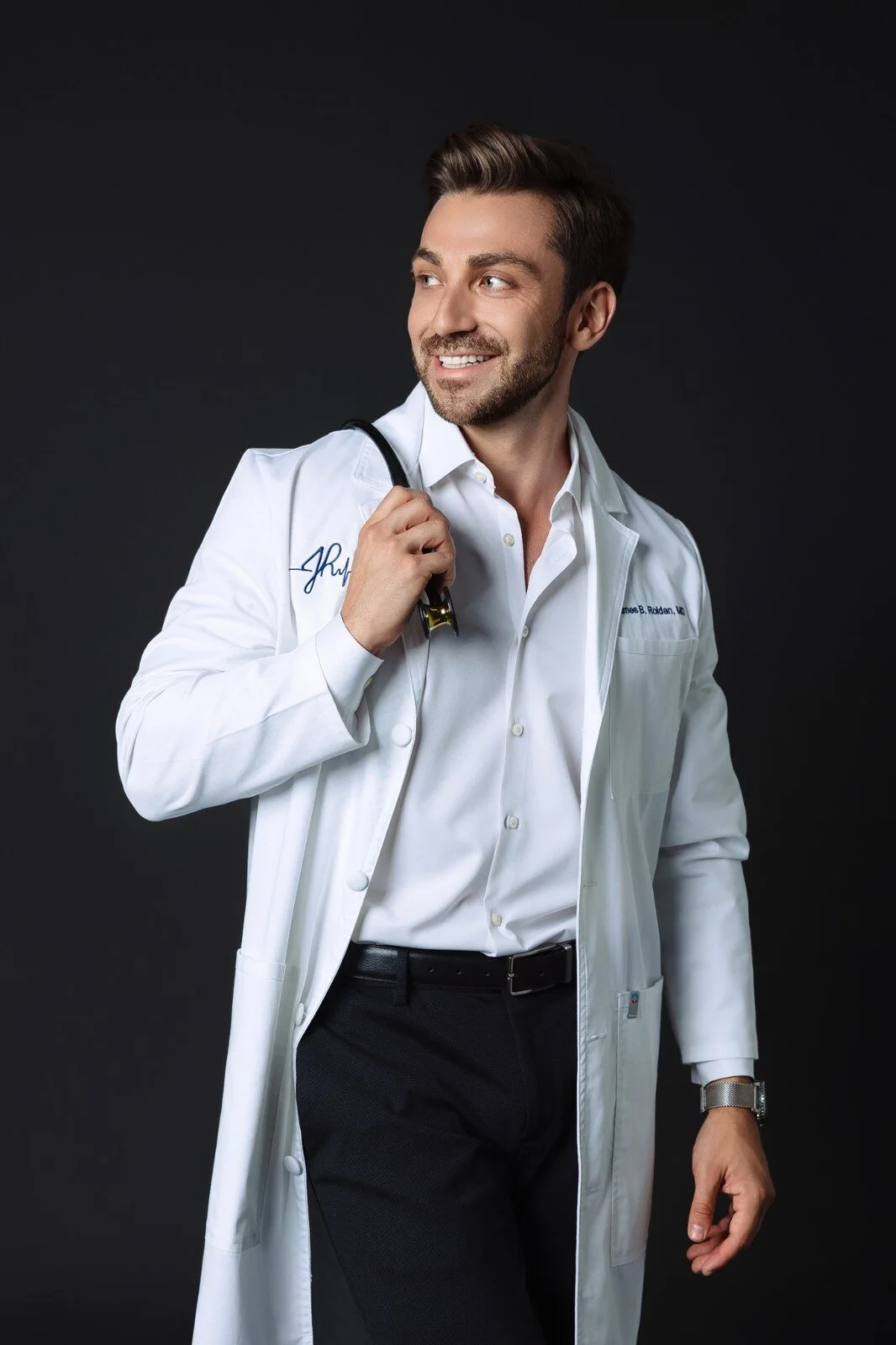 James Roldan, MD in a white coat with a stethoscope in a studio portrait.