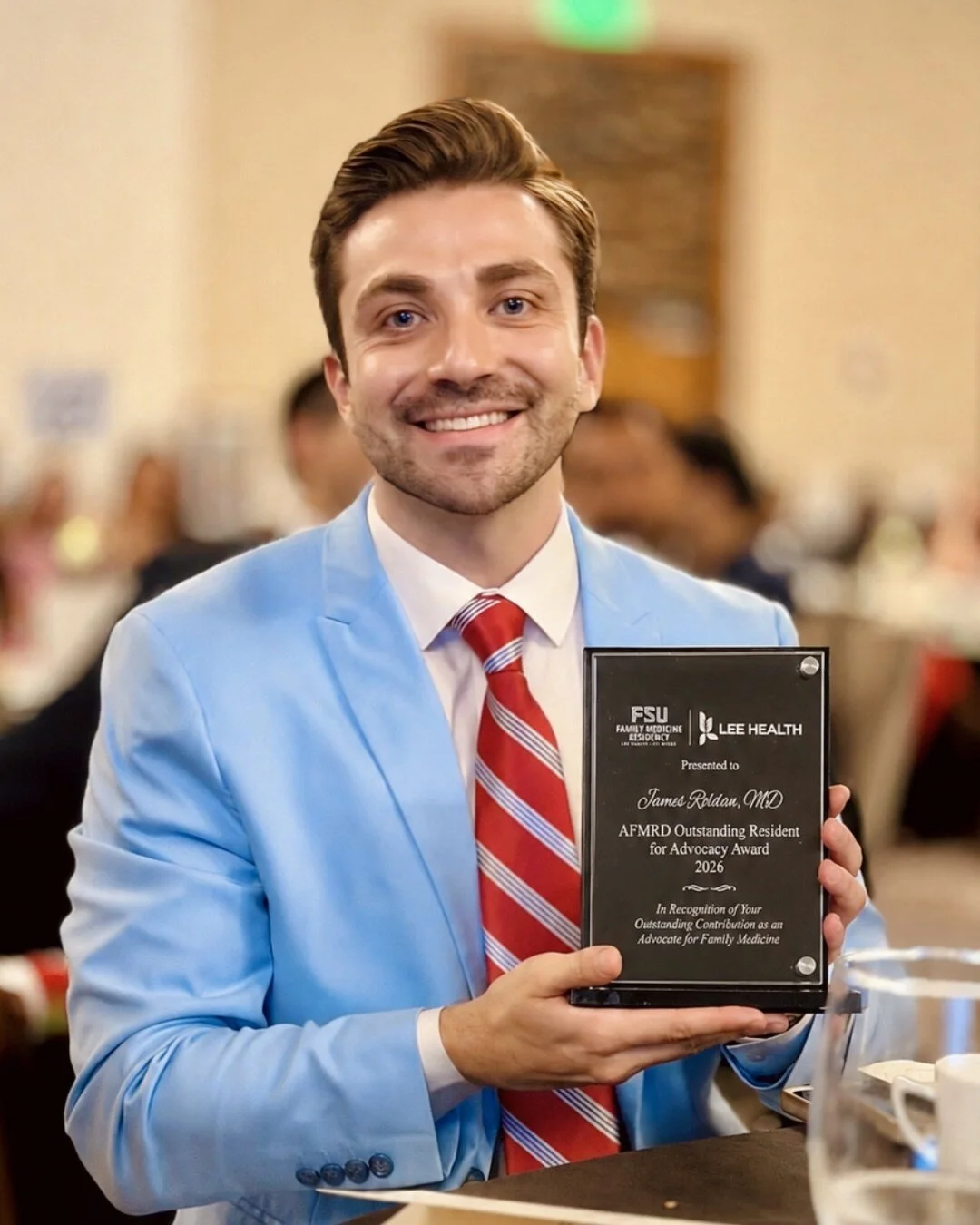 James Roldan, MD holding the 2026 AFMRD Outstanding Resident for Advocacy Award.