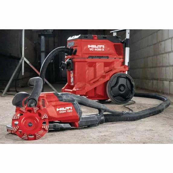 Red Hilti vacuum and angle grinder on concrete floor in a workshop.