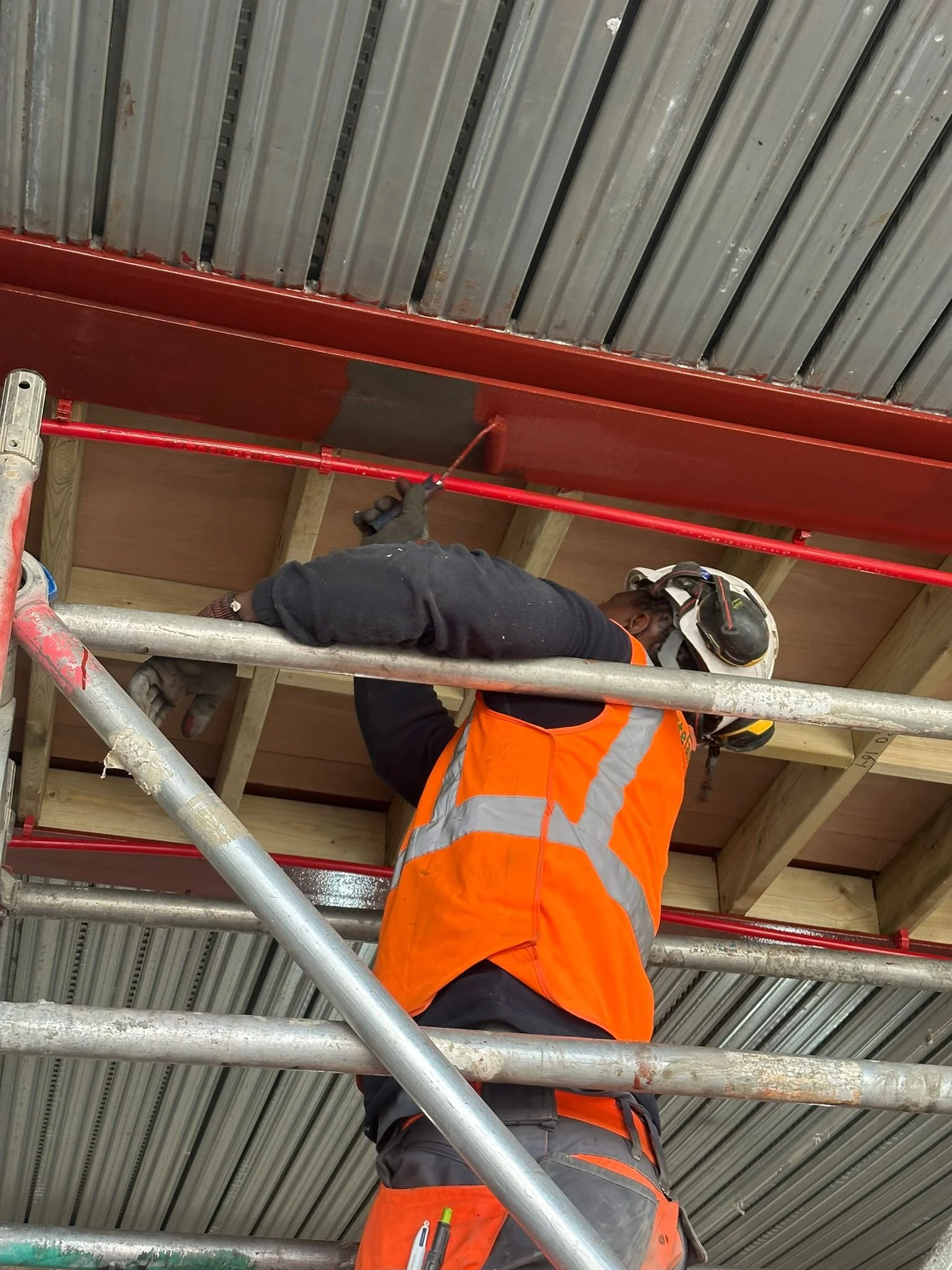 Worker in safety gear installing or inspecting a metal roofing ceiling.