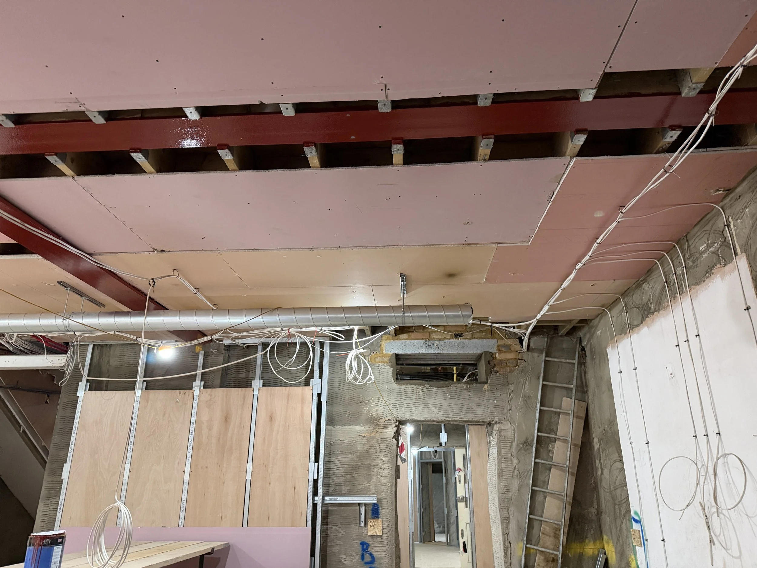 Interior of a building under construction with exposed electrical wiring, drywall, and metal framing.