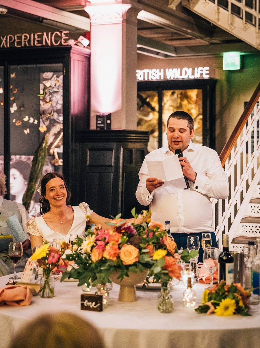 Grooms speech with bright colourful summer flower table arrangement