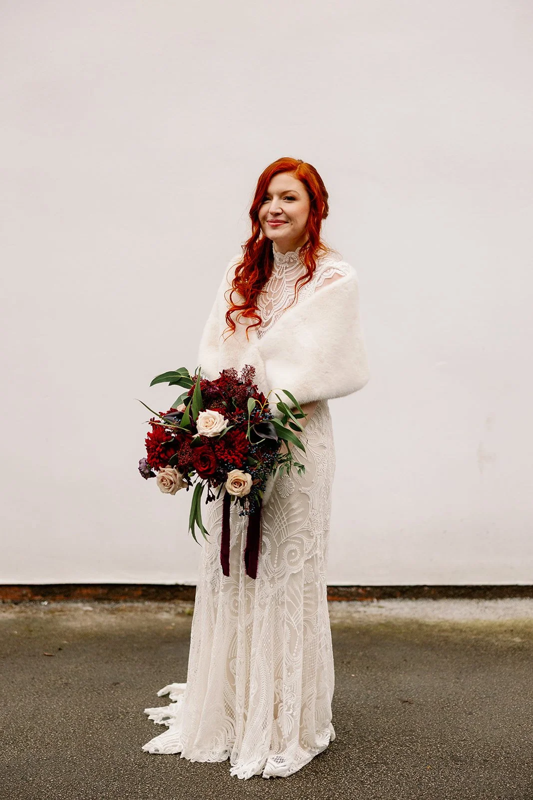Winter bride holding beautiful moody red bouquet