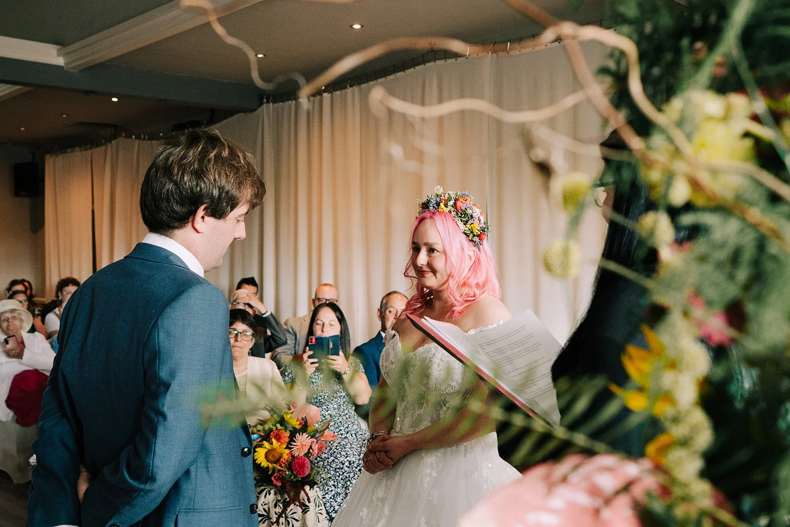 Colourful wedding couple behind colourful split arch created by MillieBuds Colour Loving Wedding Florist in Stockport at Bowdon Rooms