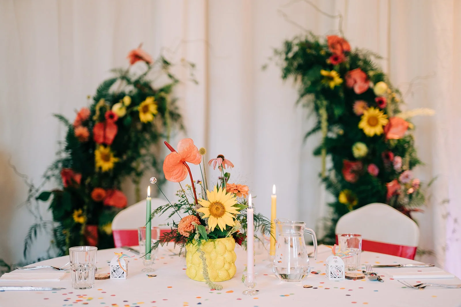 Colourful whimsical arch with colourful yellow table vase arrangement created by MillieBuds, Stcokport