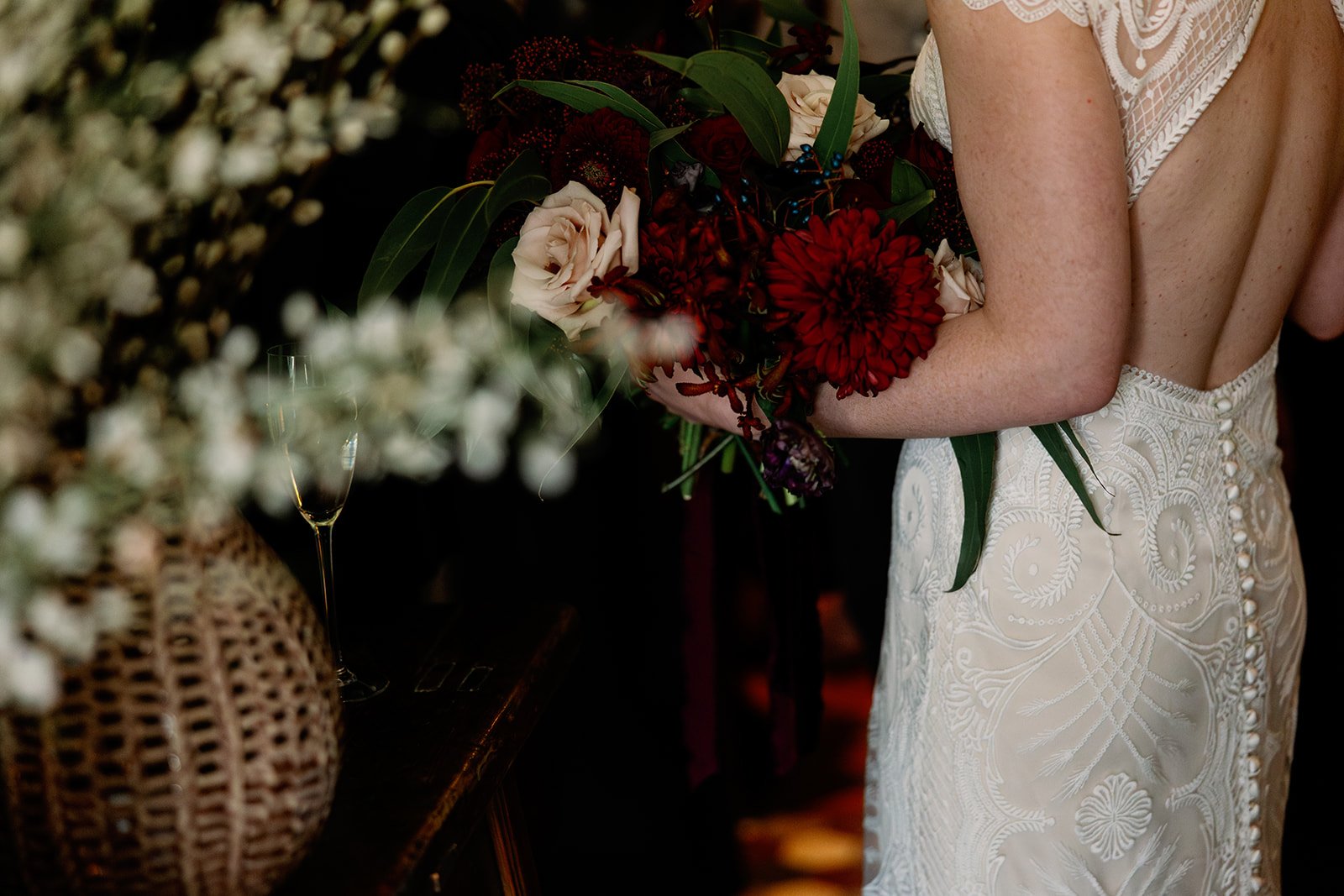 Side shot of bride holding moody red wedding bouquet
